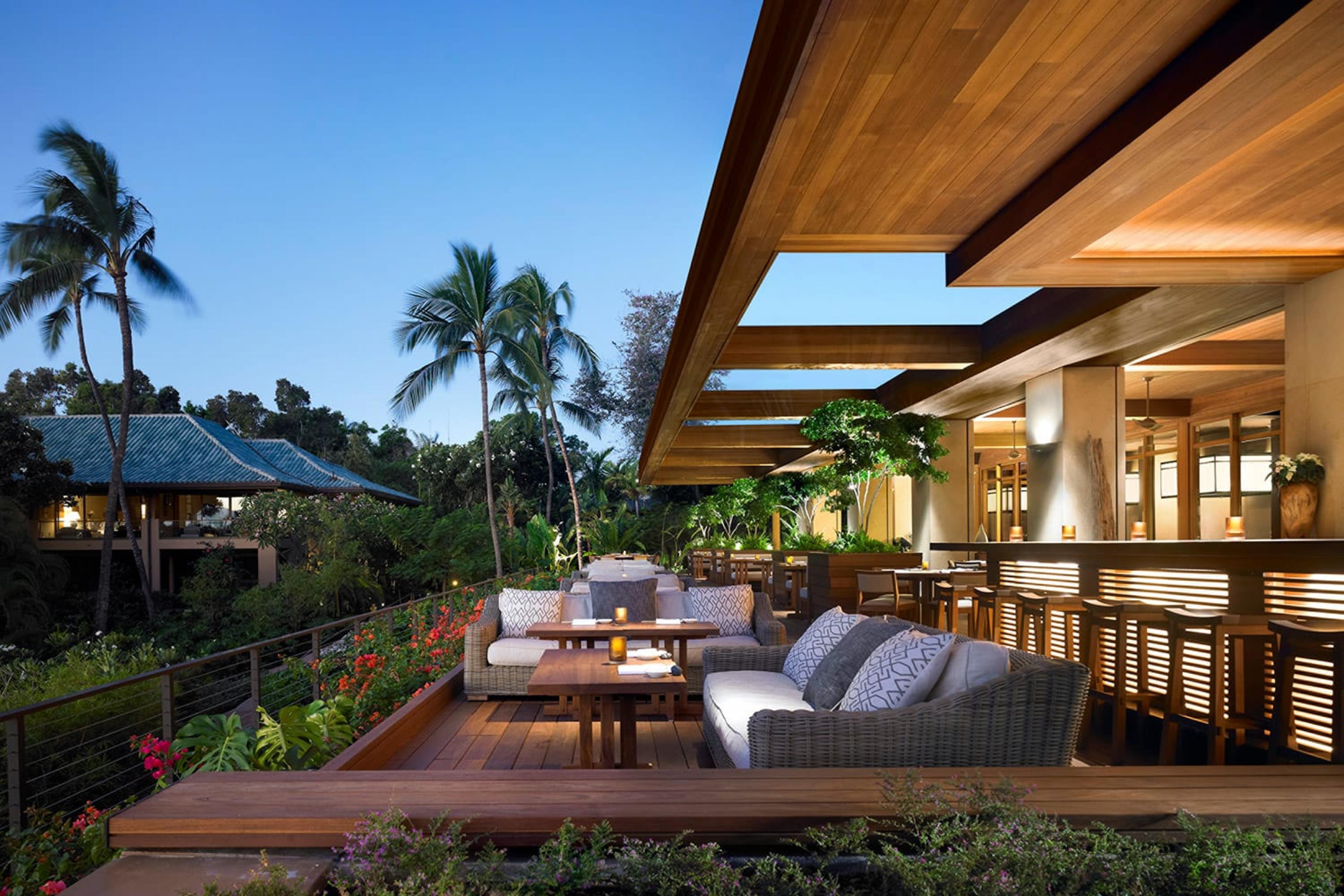 wooden terrace with couch seating at evening time in hawaii with palm trees in background