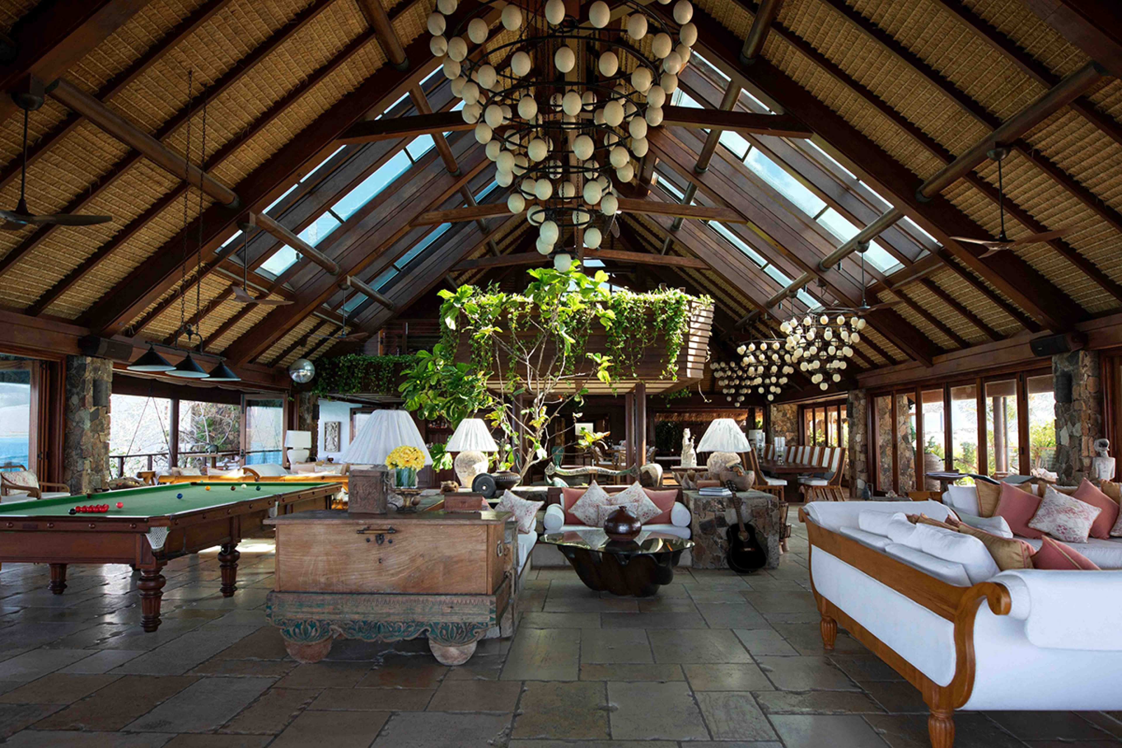 Lounge area with tables and chairs and a pool table in a large open air hut