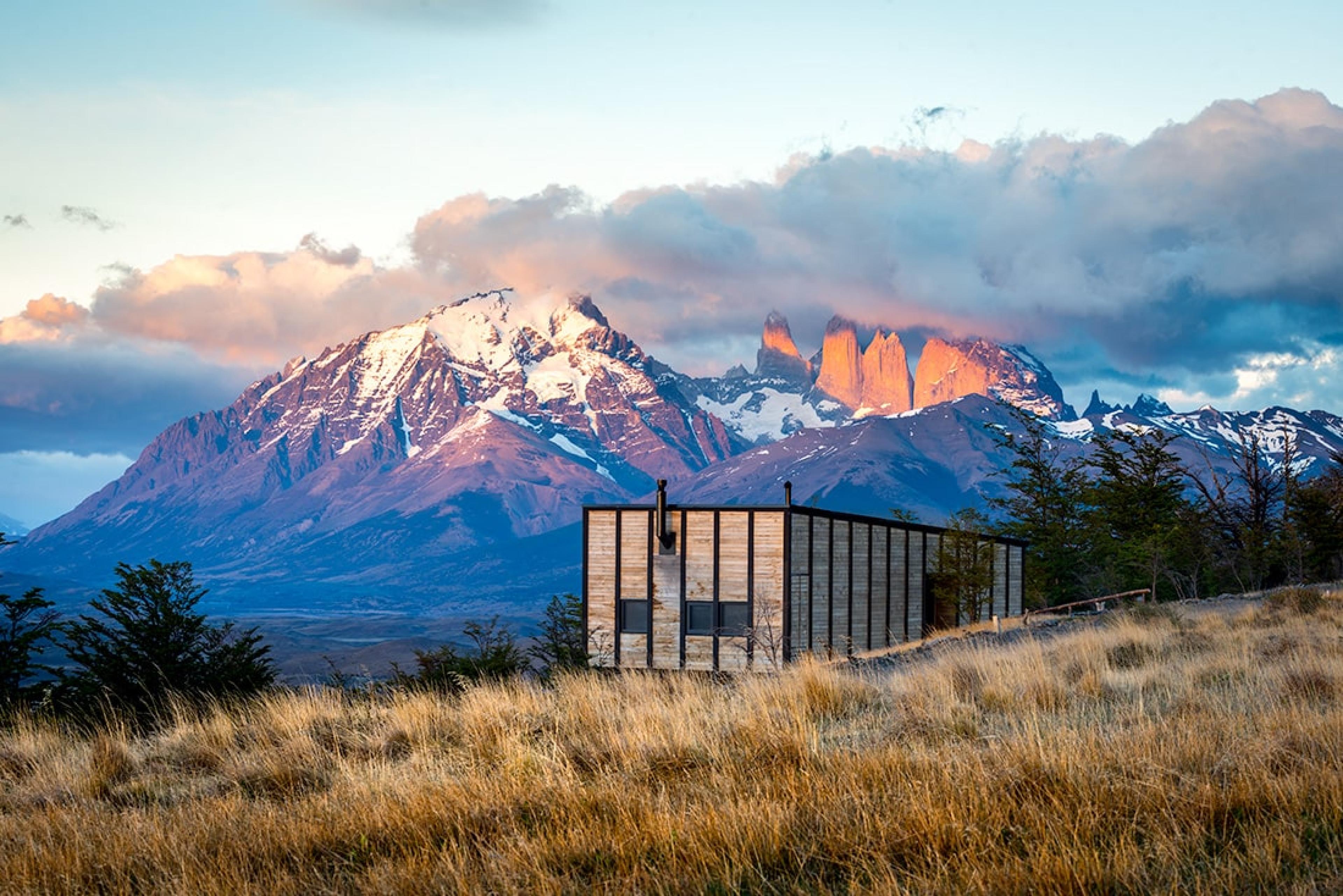 wooden rectangular cabin on hill with view of large stone mountain in background