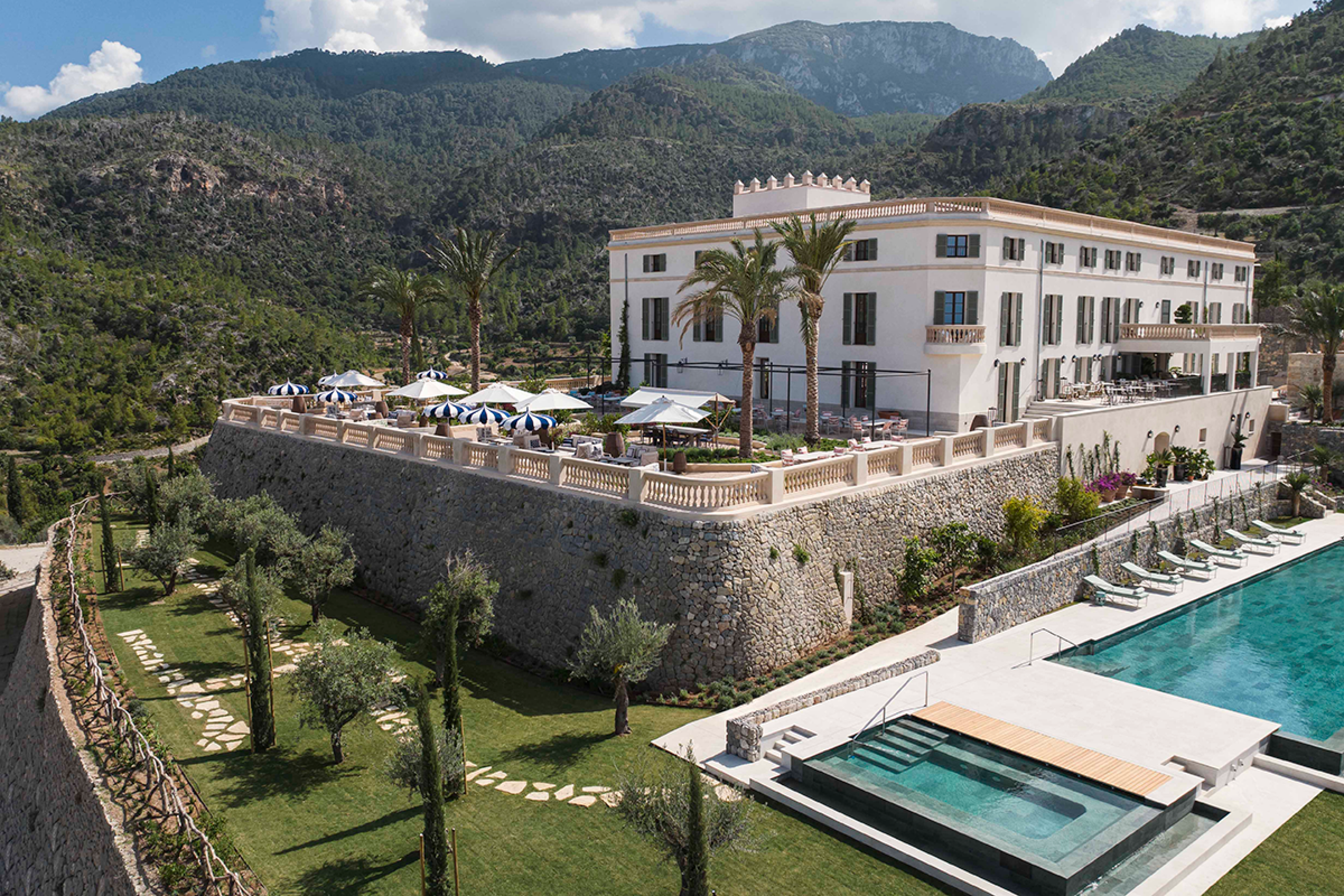 white hotel set up on a stone terrace with a large rectangular pool