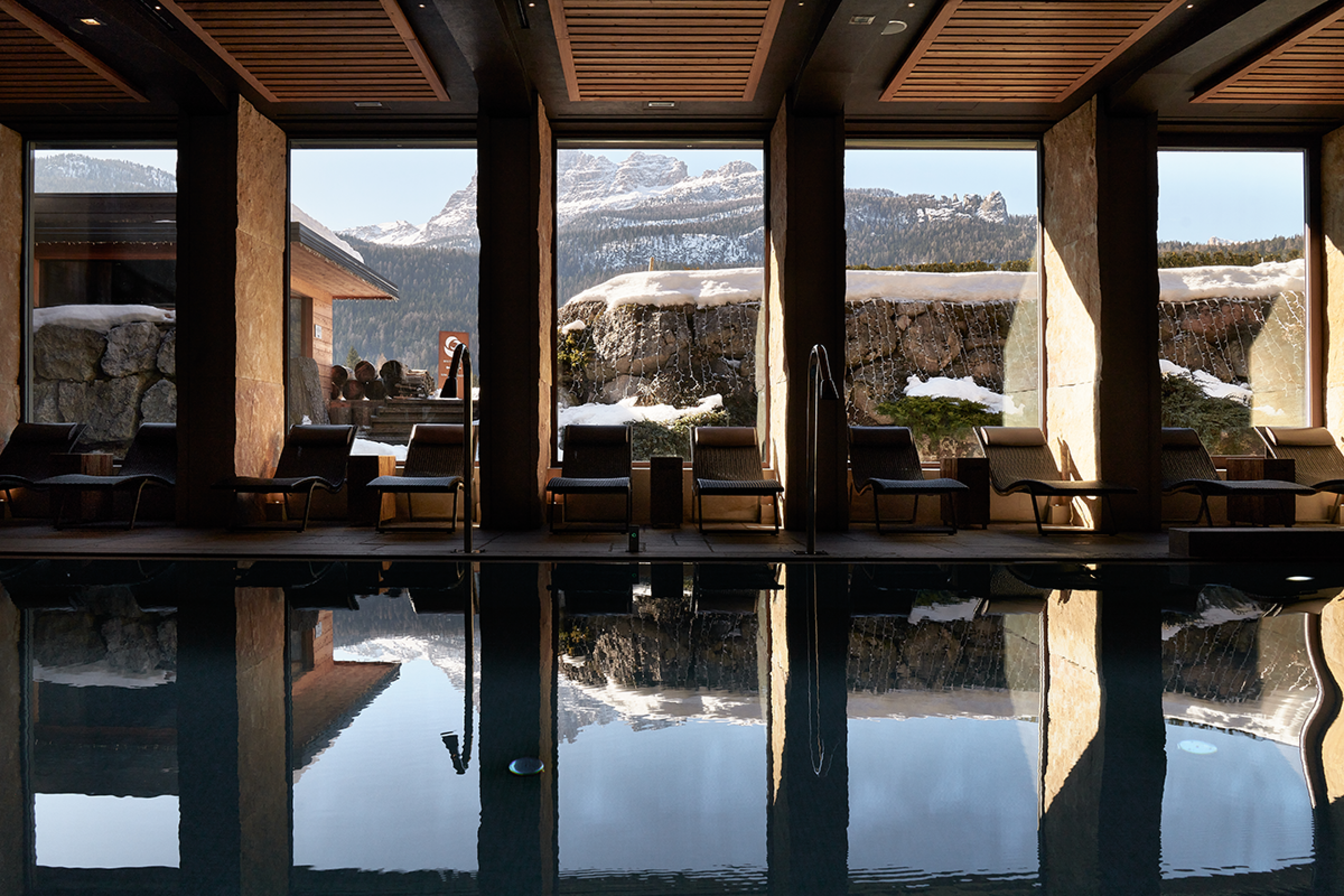 swimming pool lined with floor to ceiling windows overlooking mountains