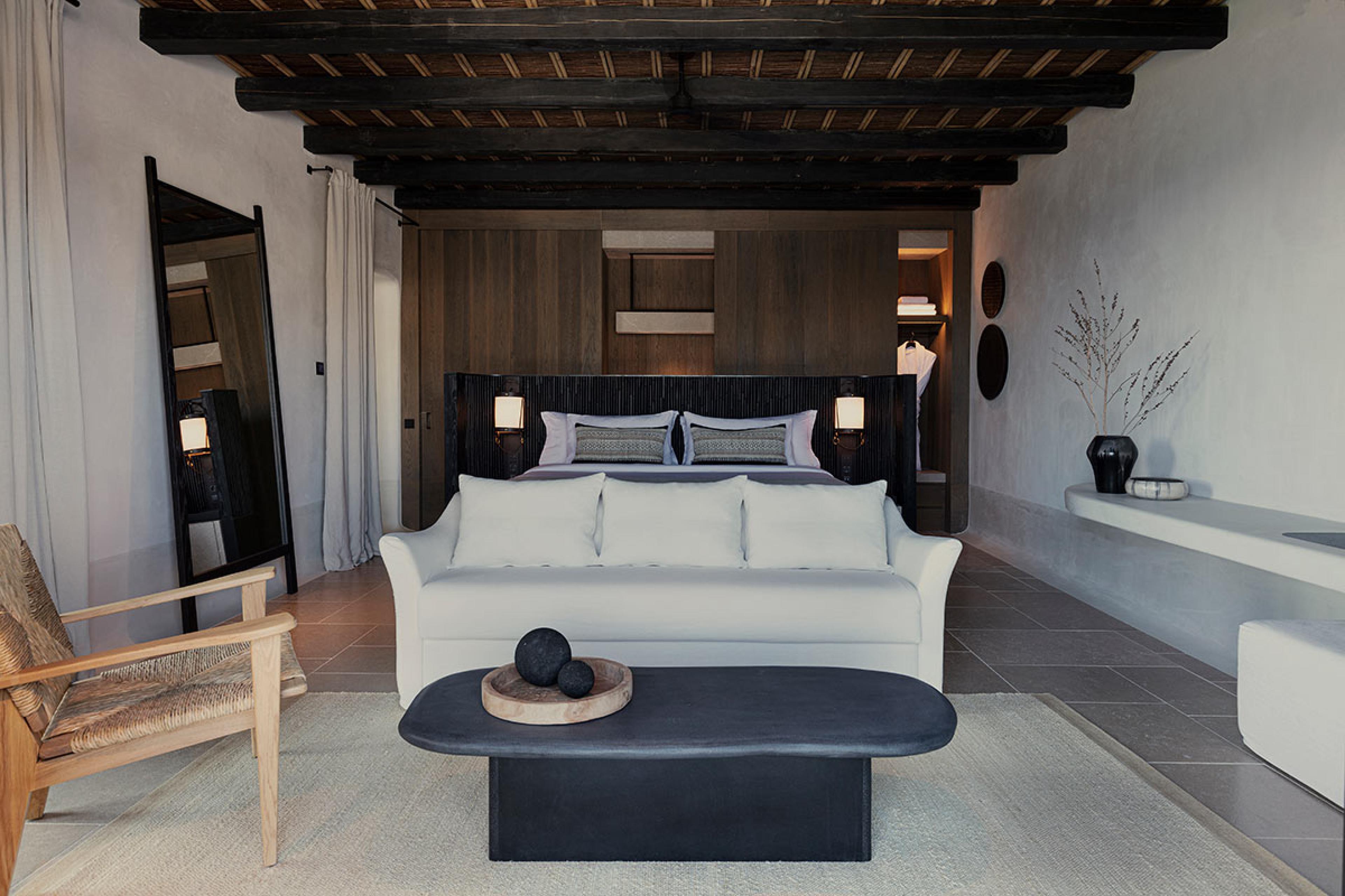 Kalesma Mykonos Suite  with couch at the foot of bed and large black stone coffee table