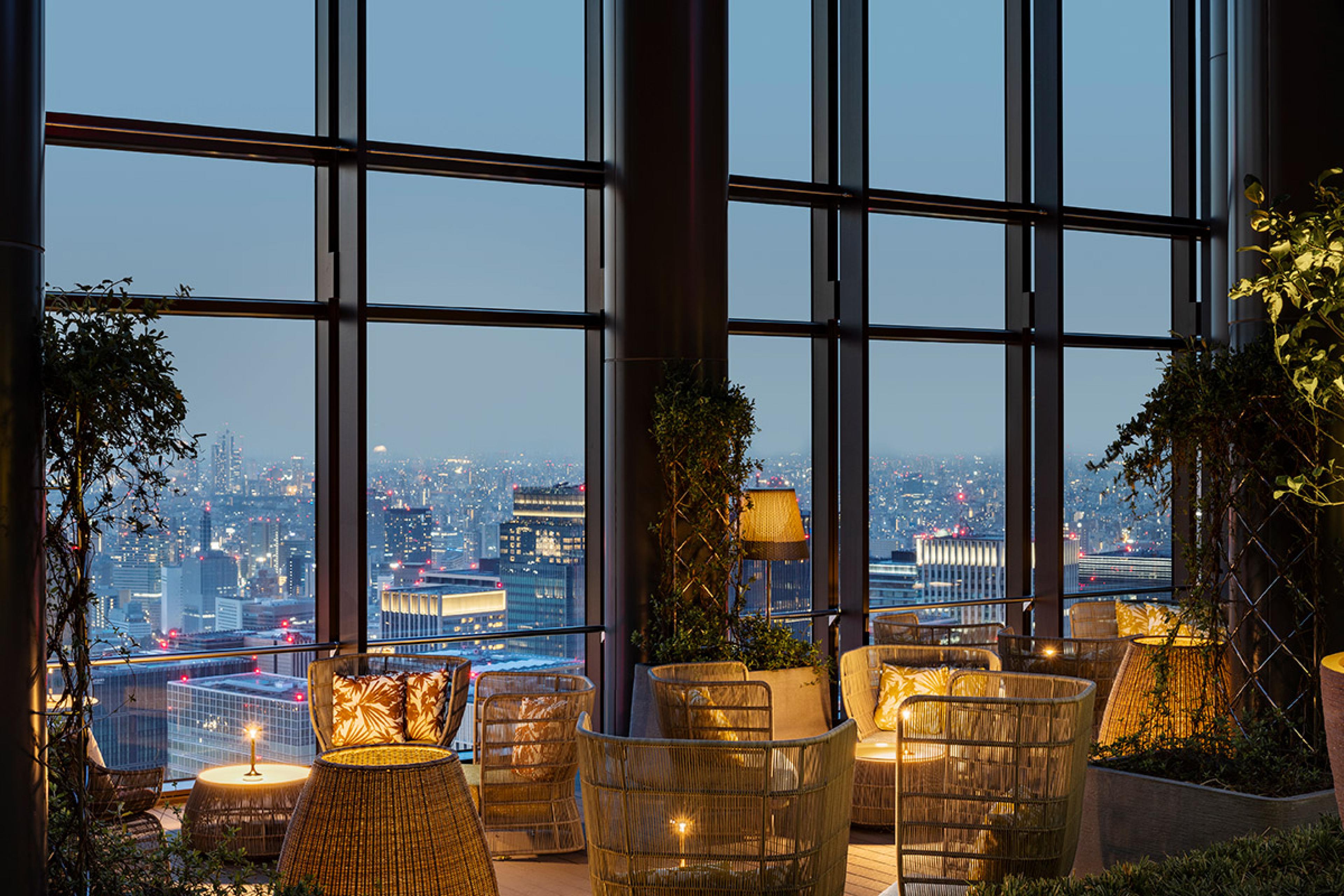 seating near glass wall of tall skyscraper at dusk 