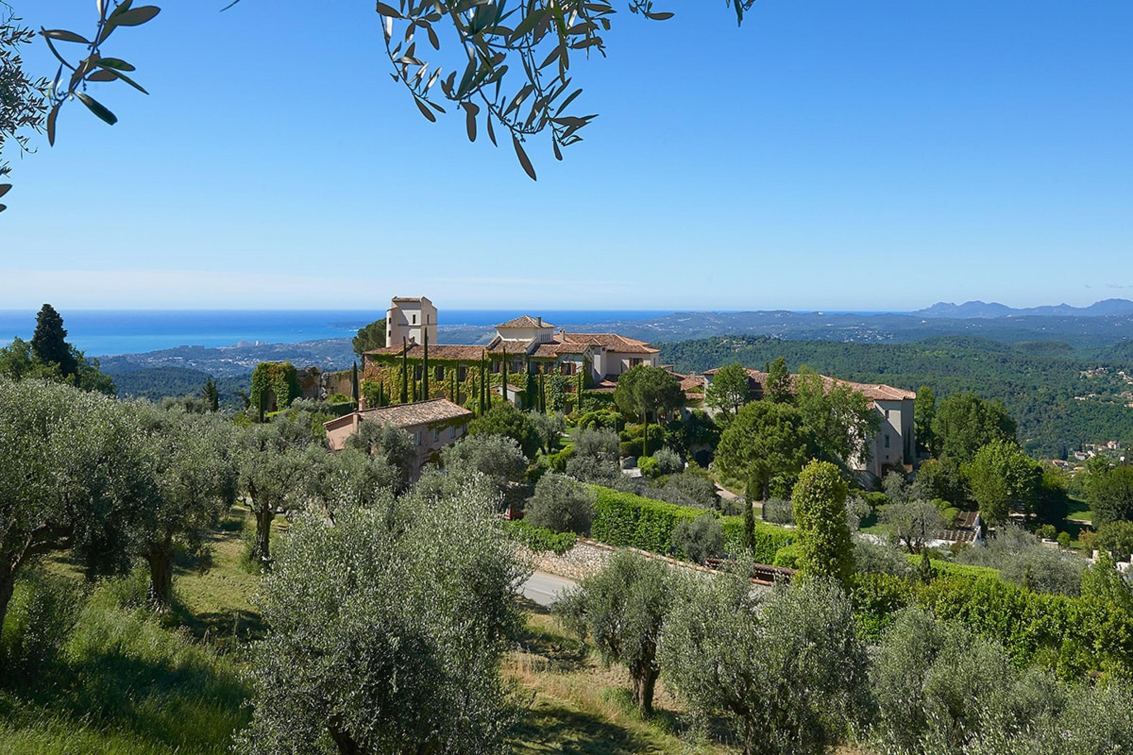 view of chateau building peeking through olive groves on hill overlooking south of france and mediterranean