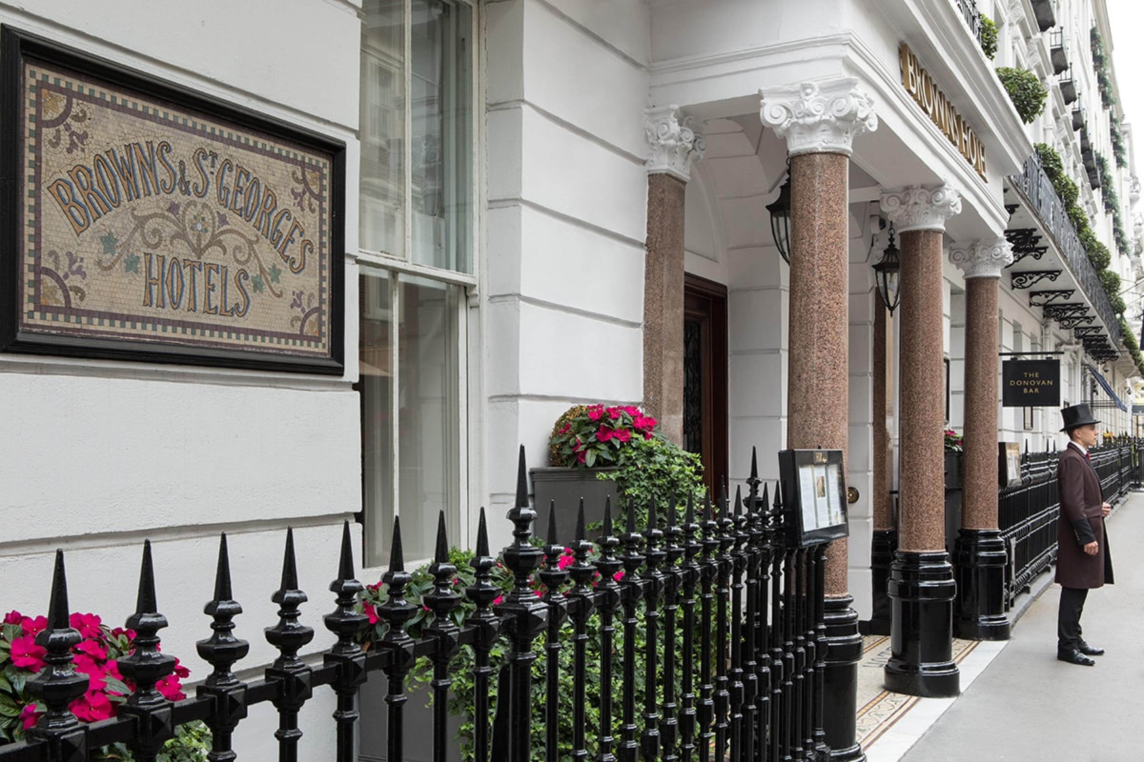 London hotel entrance on typical London street with white-stone townhomes in a row and hotel doorman