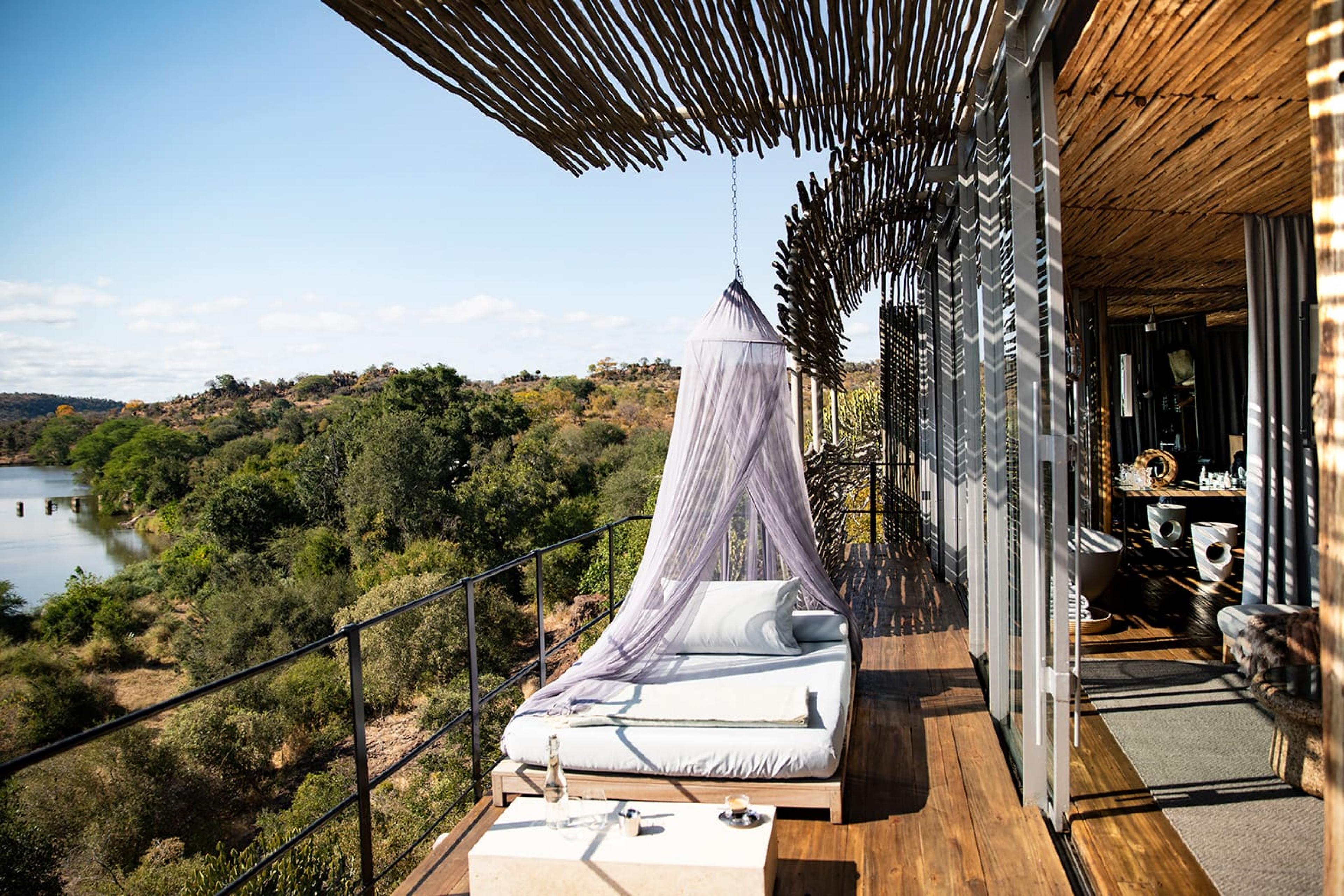 A bed on a balcony at daytime overlooking river