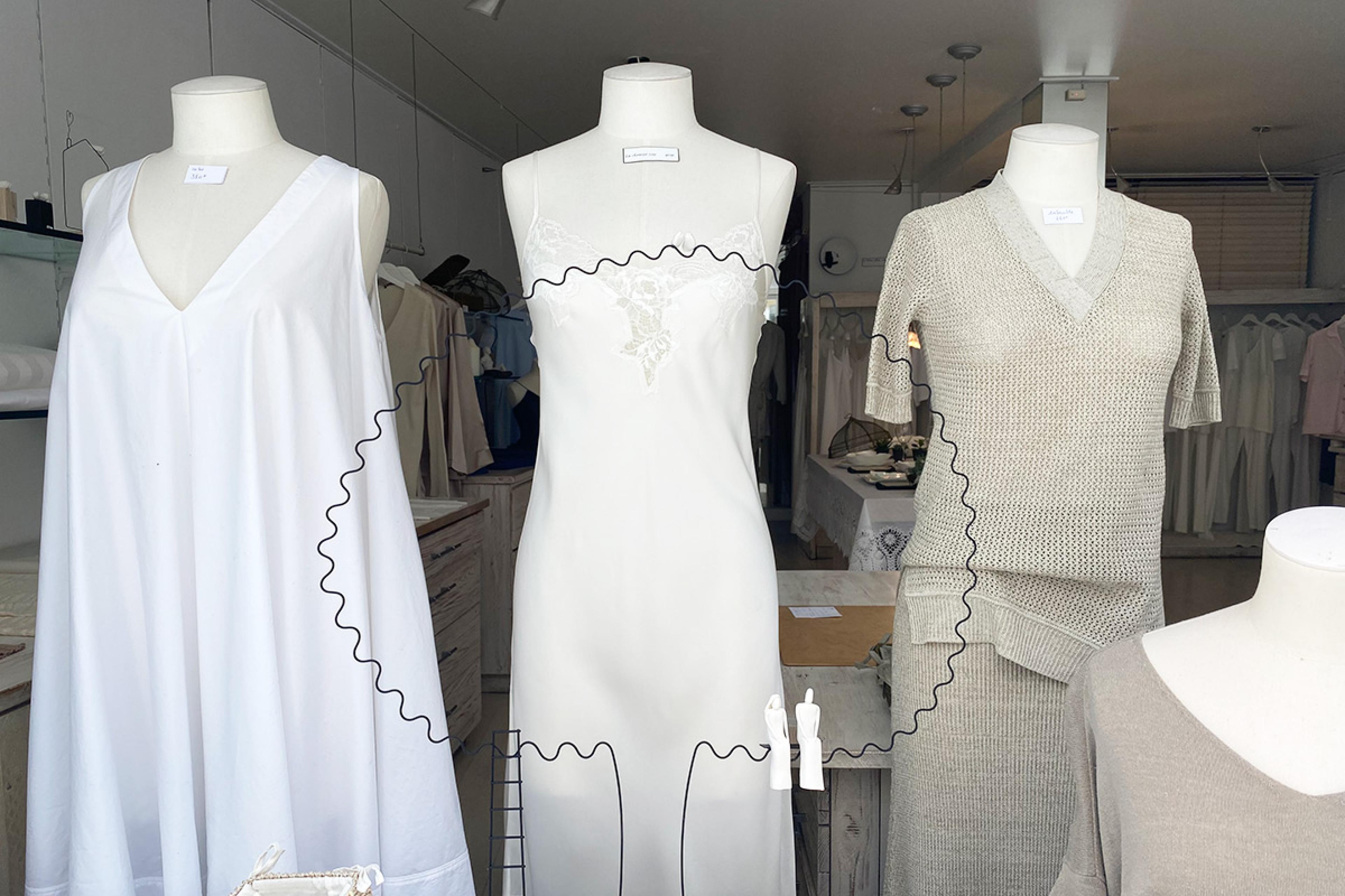 window of paris linen shop with three white and beige linen dresses seen
