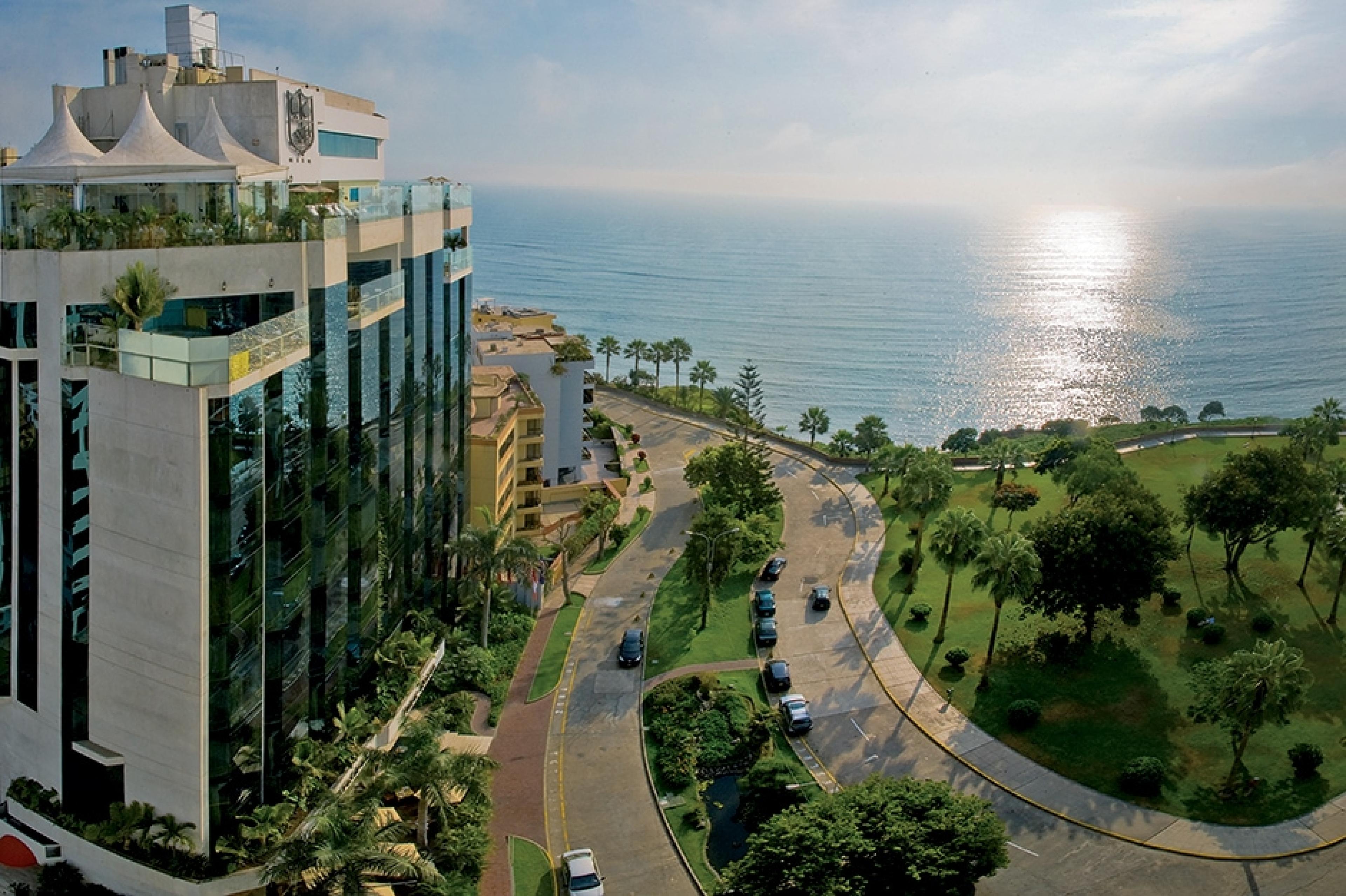 aerial view of hotel exterior. hotel has glass walls and overlooks a park and the ocean