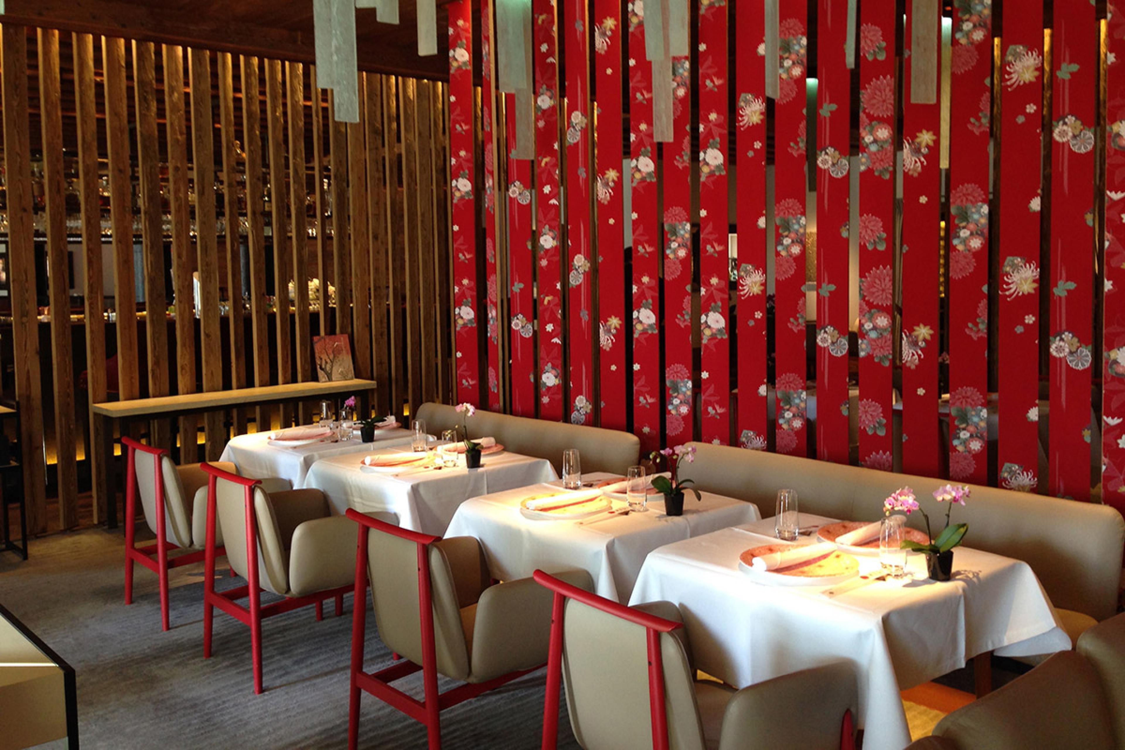 dining room at a formal contemporary restaurant with red wall art and white tablecloths
