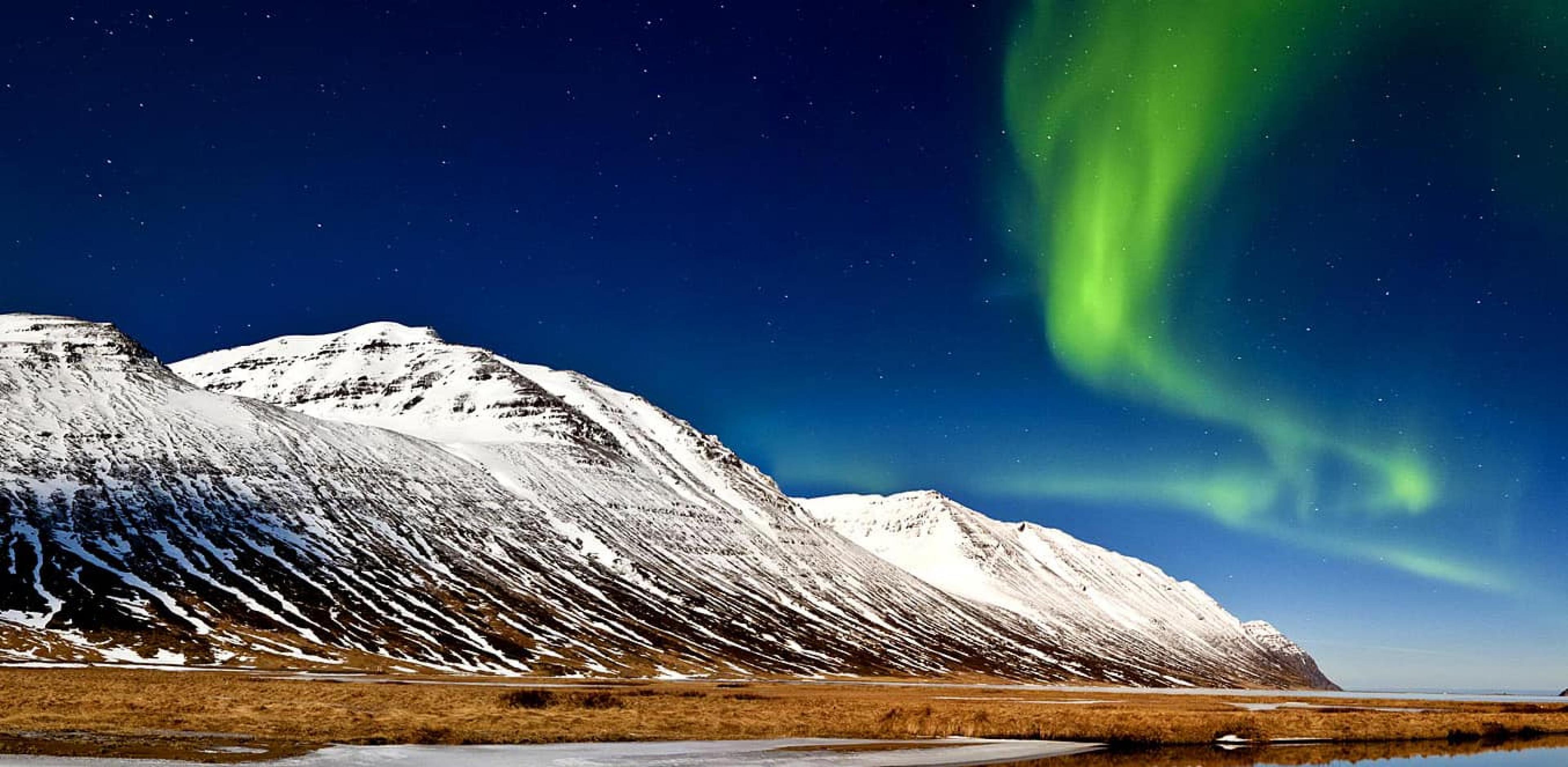 Aurora Borealis over snowy mountain in Iceland