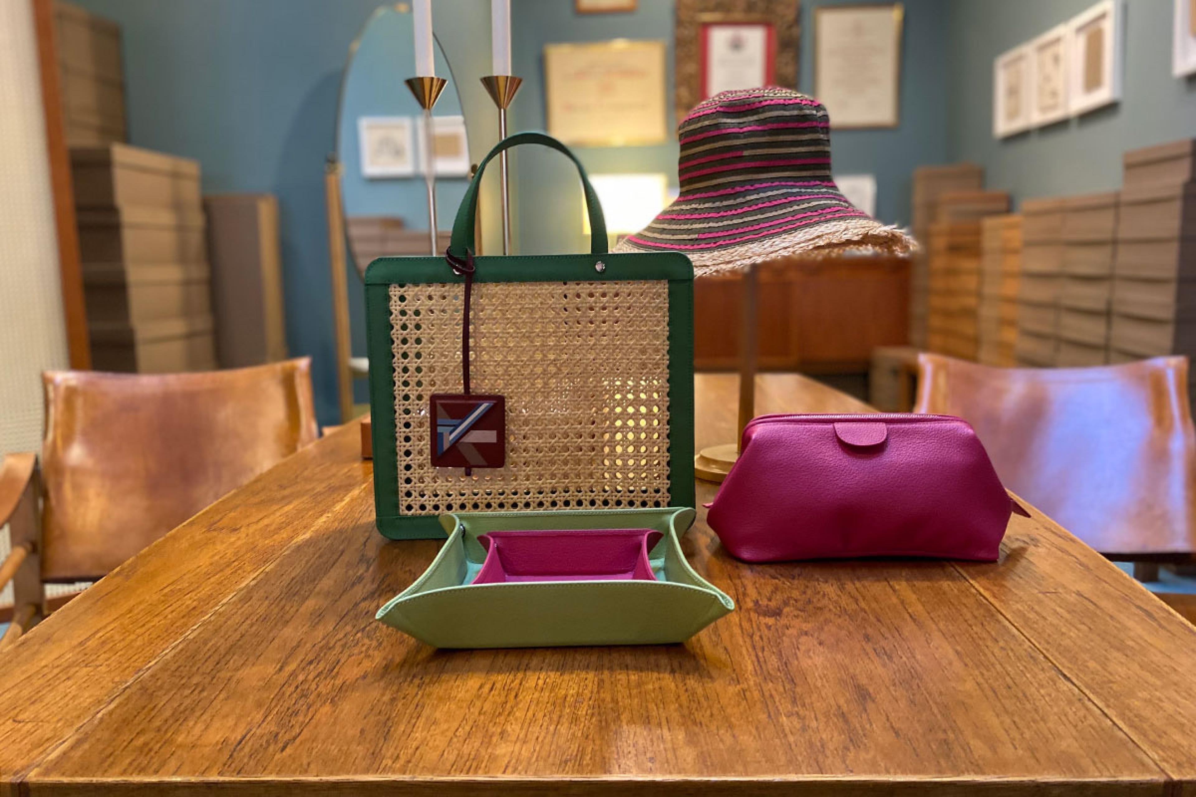 colorful leather and straw purses and a clutch and other goods on a wooden table