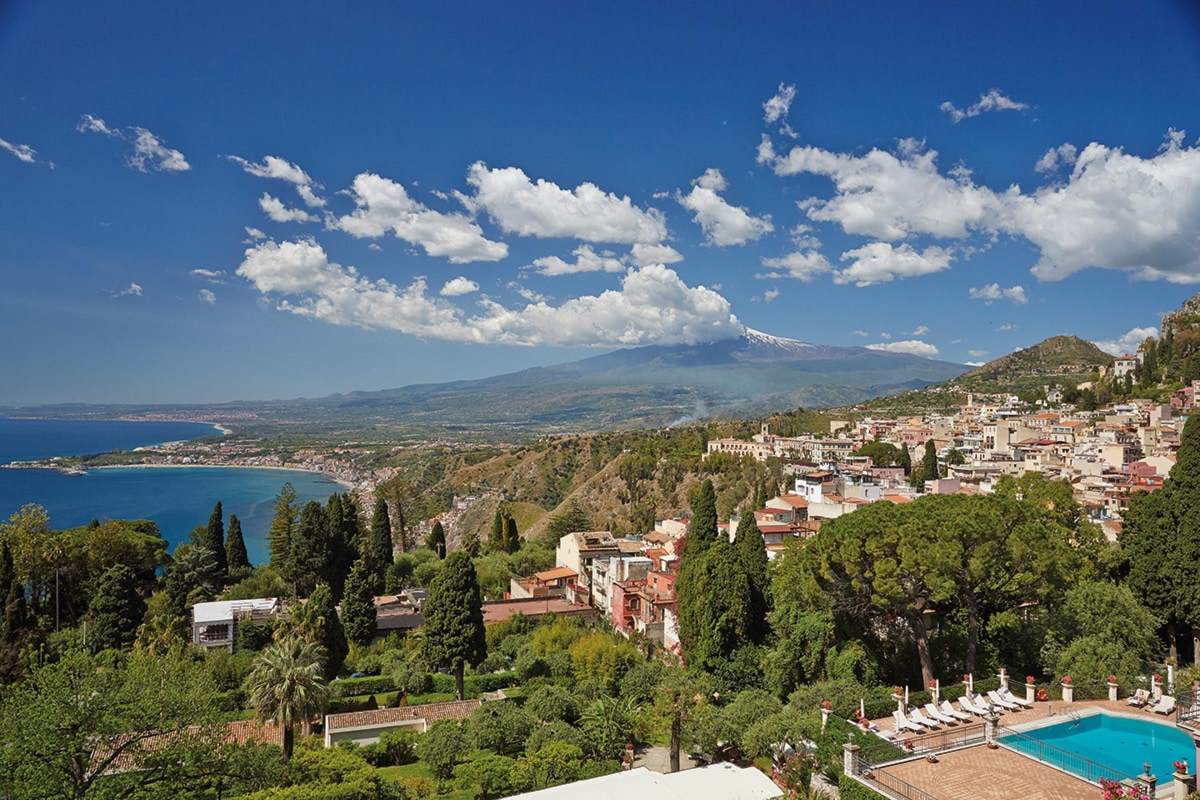 view over hotel grounds in sicily with pool to the right and aetna volcano in background
