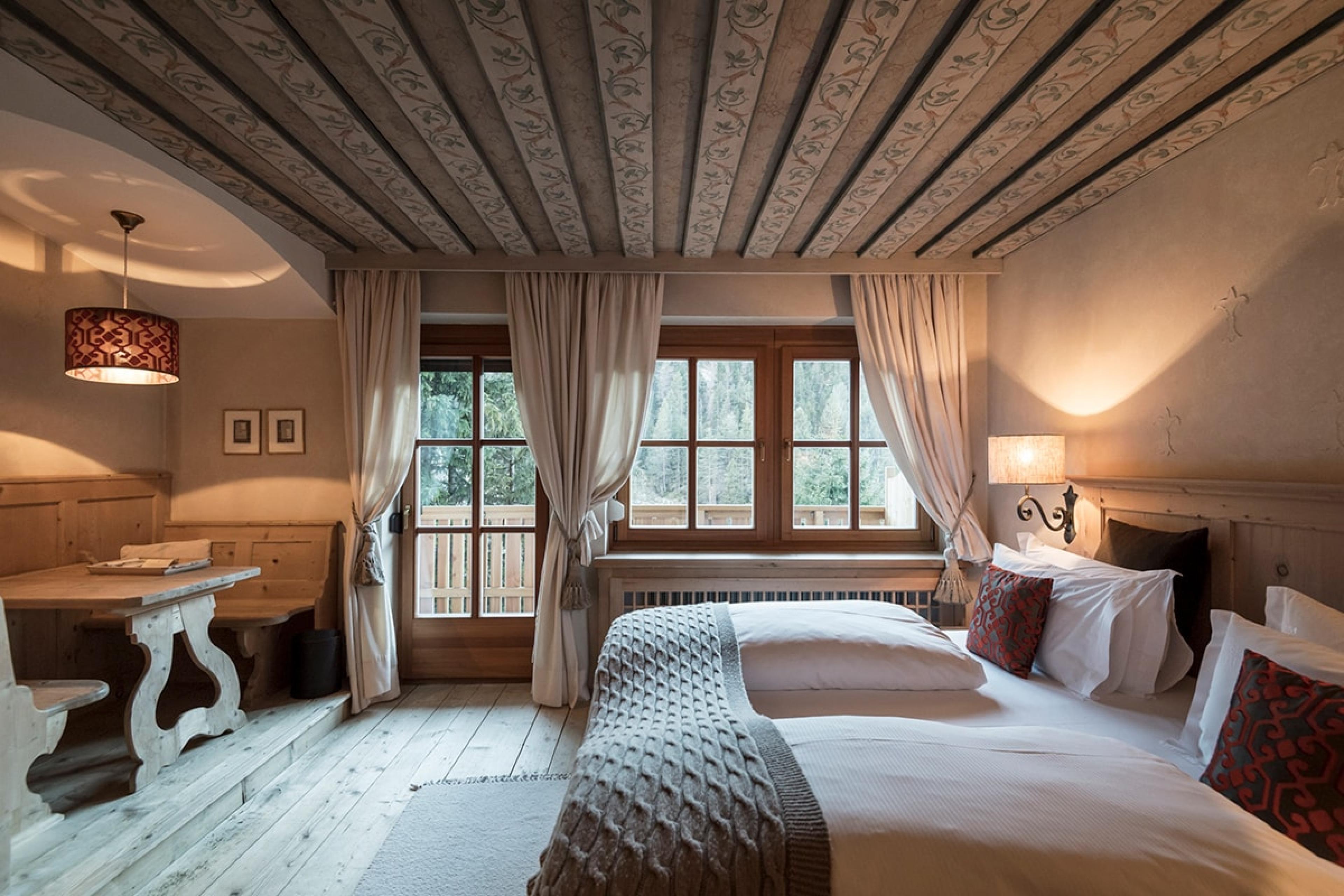 bedroom in european alpine chalet hotel with painted ceiling and two beds with duvets on them
