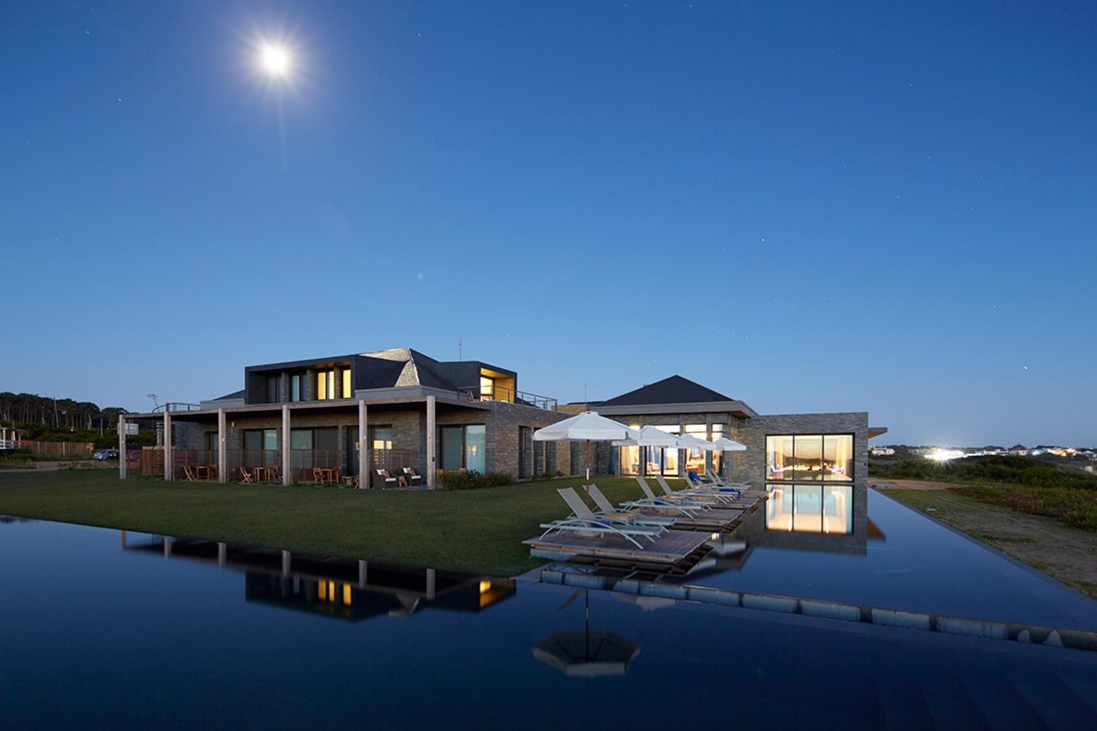 at night with a full moon, a house and L-shaped pool