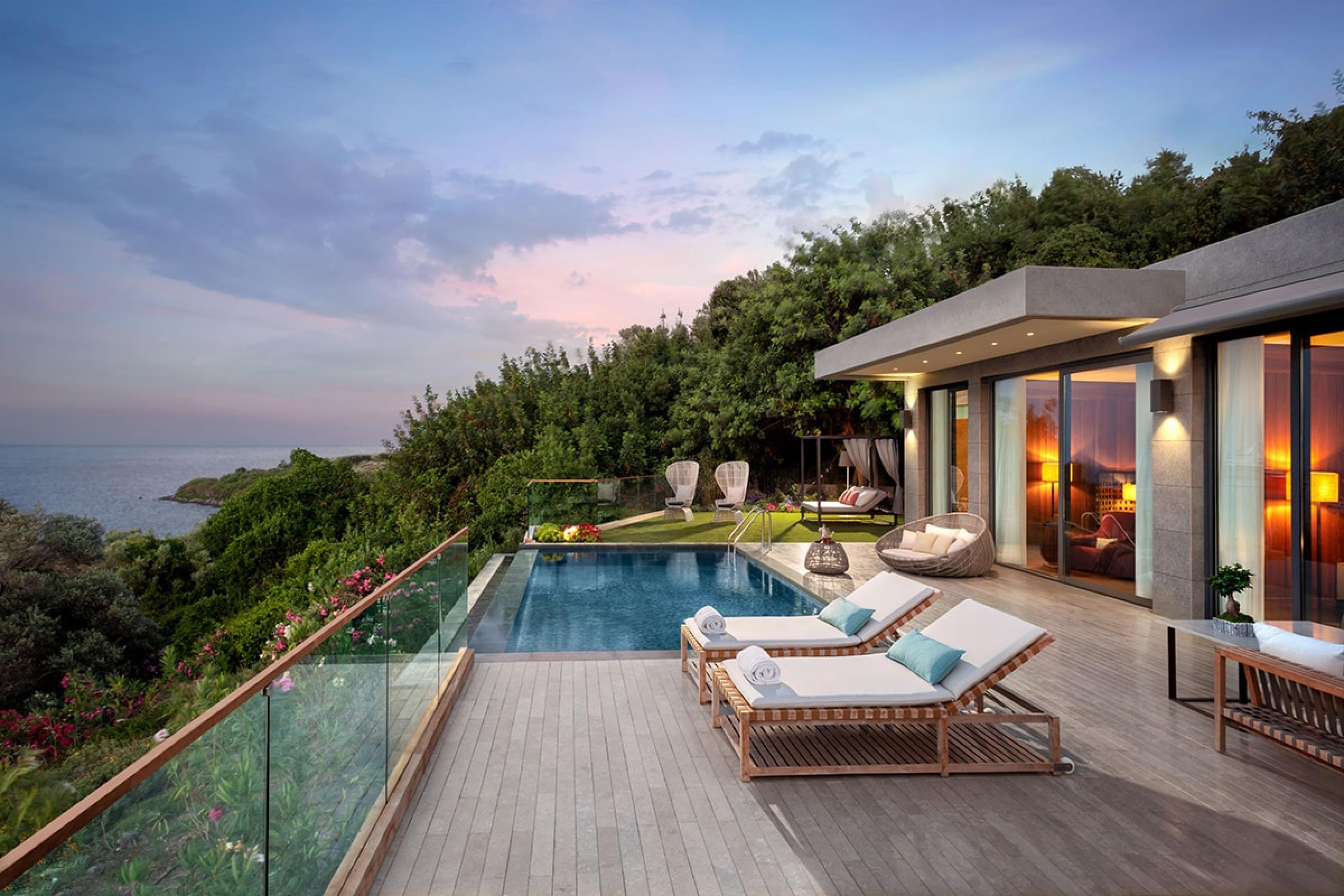 hotel suite terrace with private plunge pool and multiple lounge chairs looking out over hill at dusk