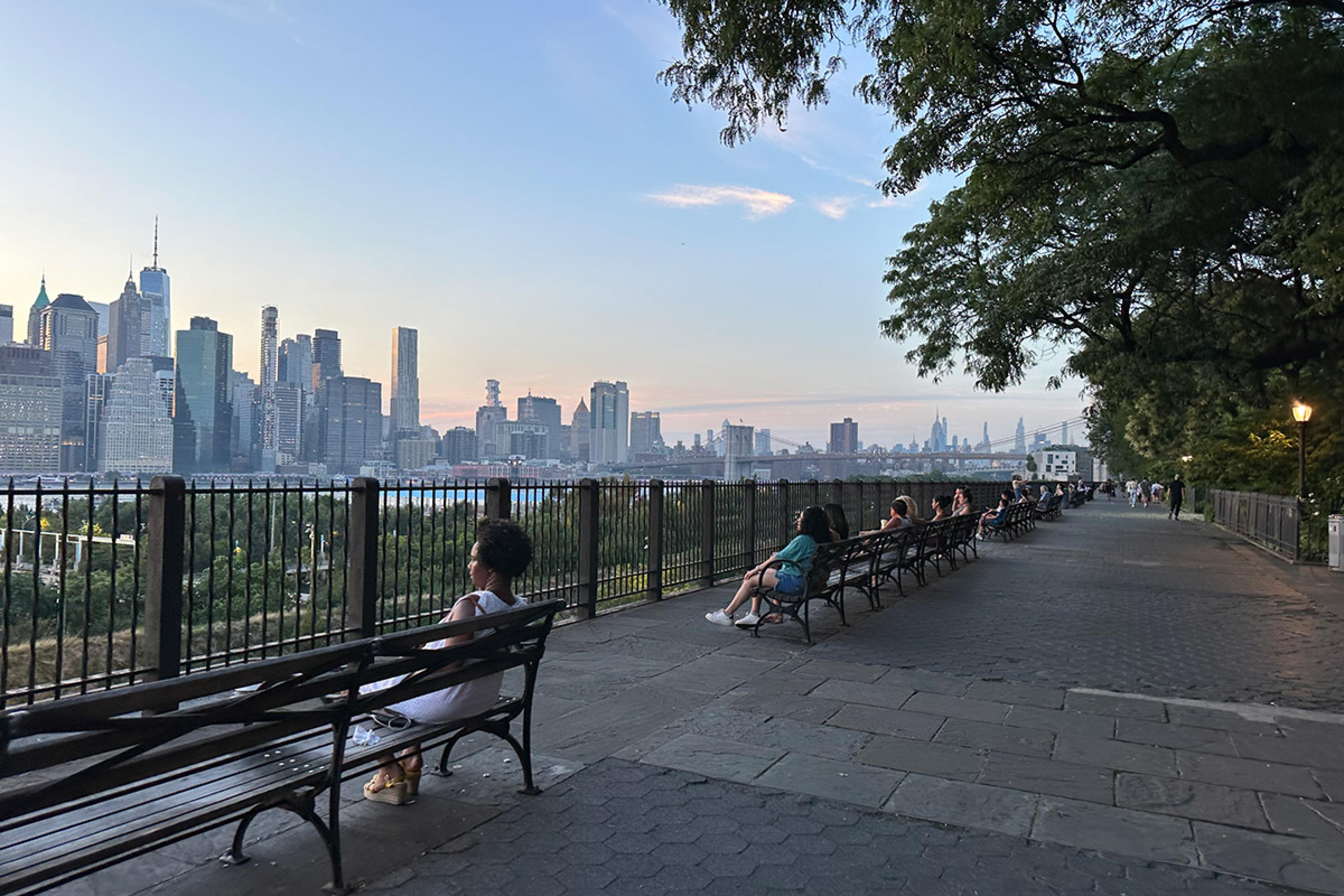long paved promenade with view of nyc skyline across water