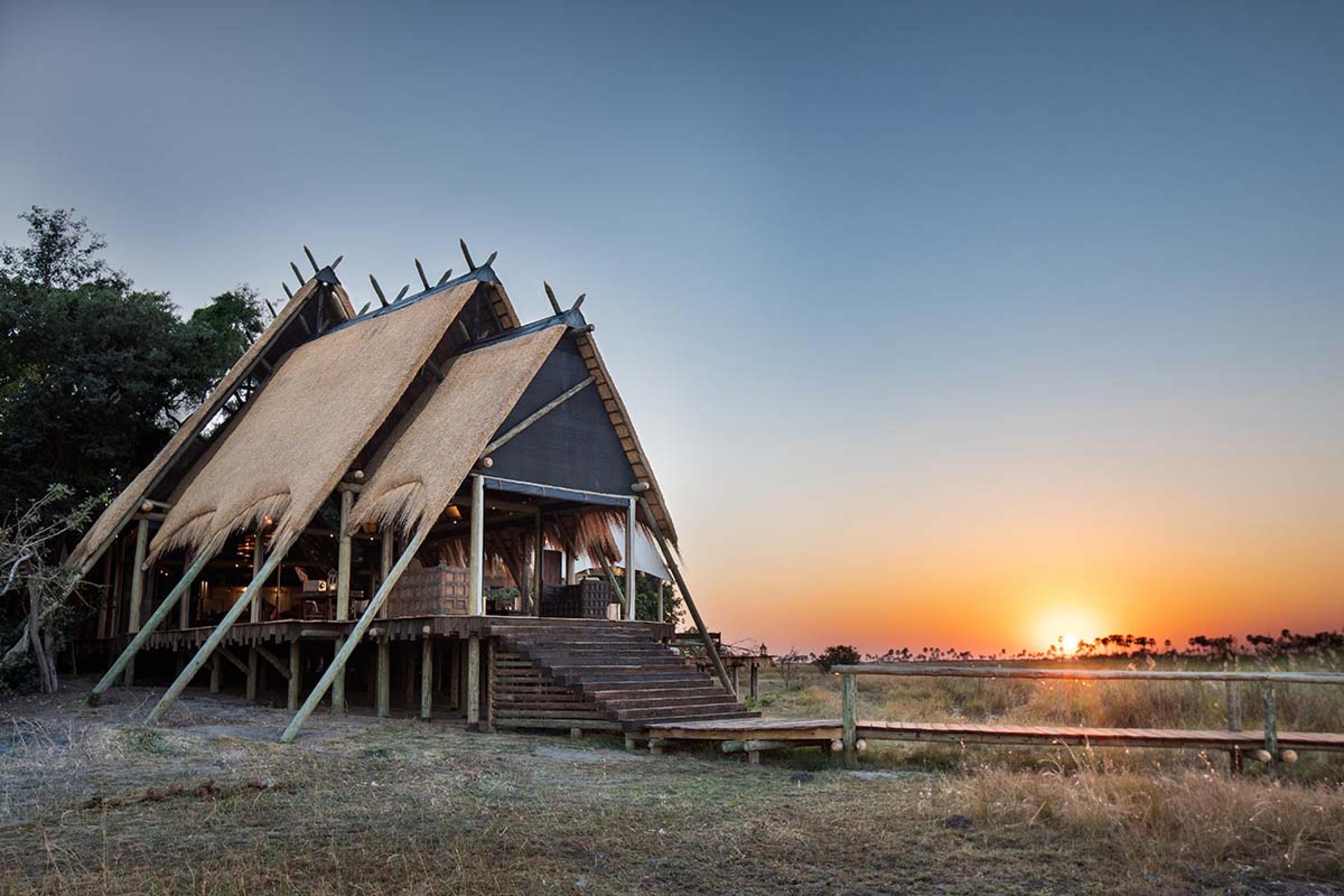 three tiered tents with a raised wooden walkway over a marsh at sunset