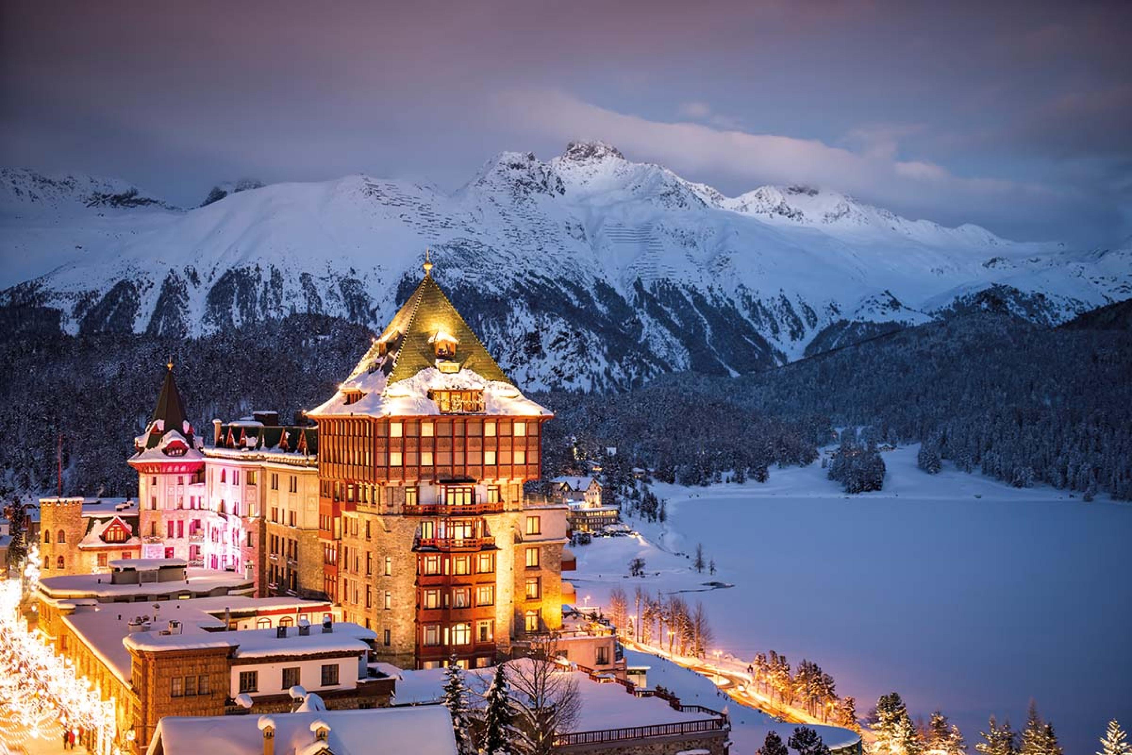 lit up building surrounded by snowy mountains