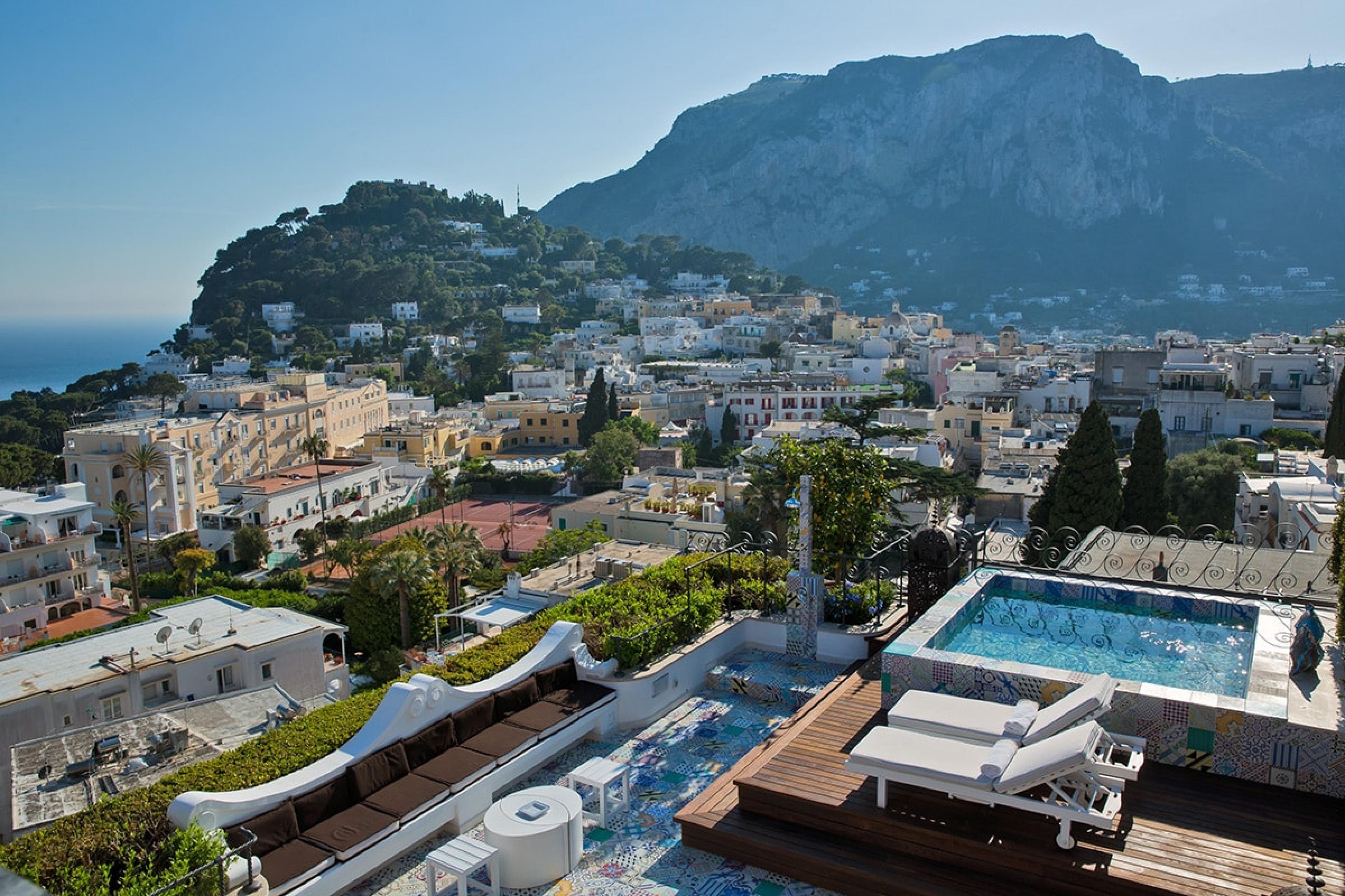 view out over wooden deck with plunge pool and views over Capri's mountains, towns and sea