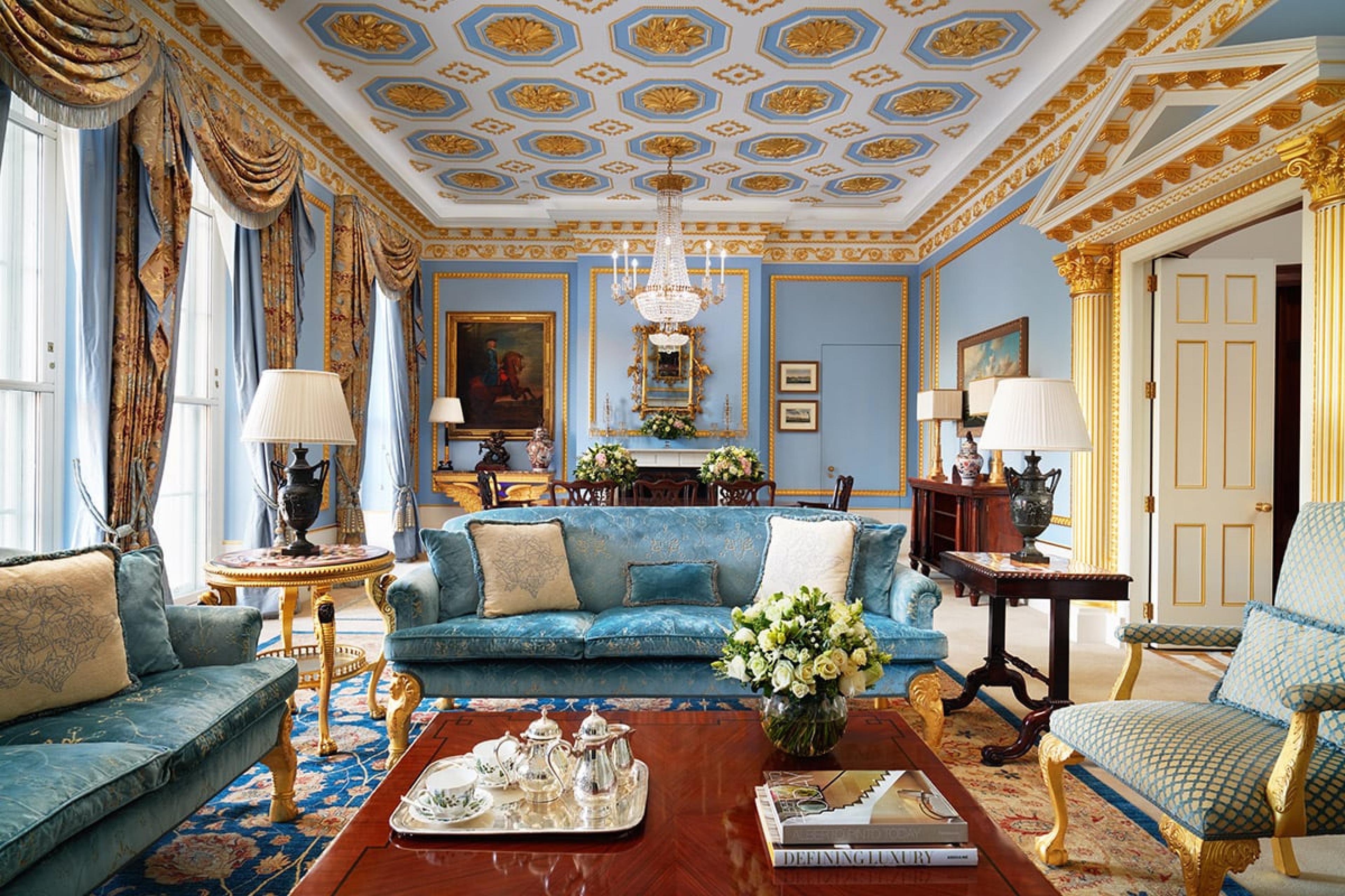 a grand hotel suite's living room with coffered gold ceiling and blue furniture