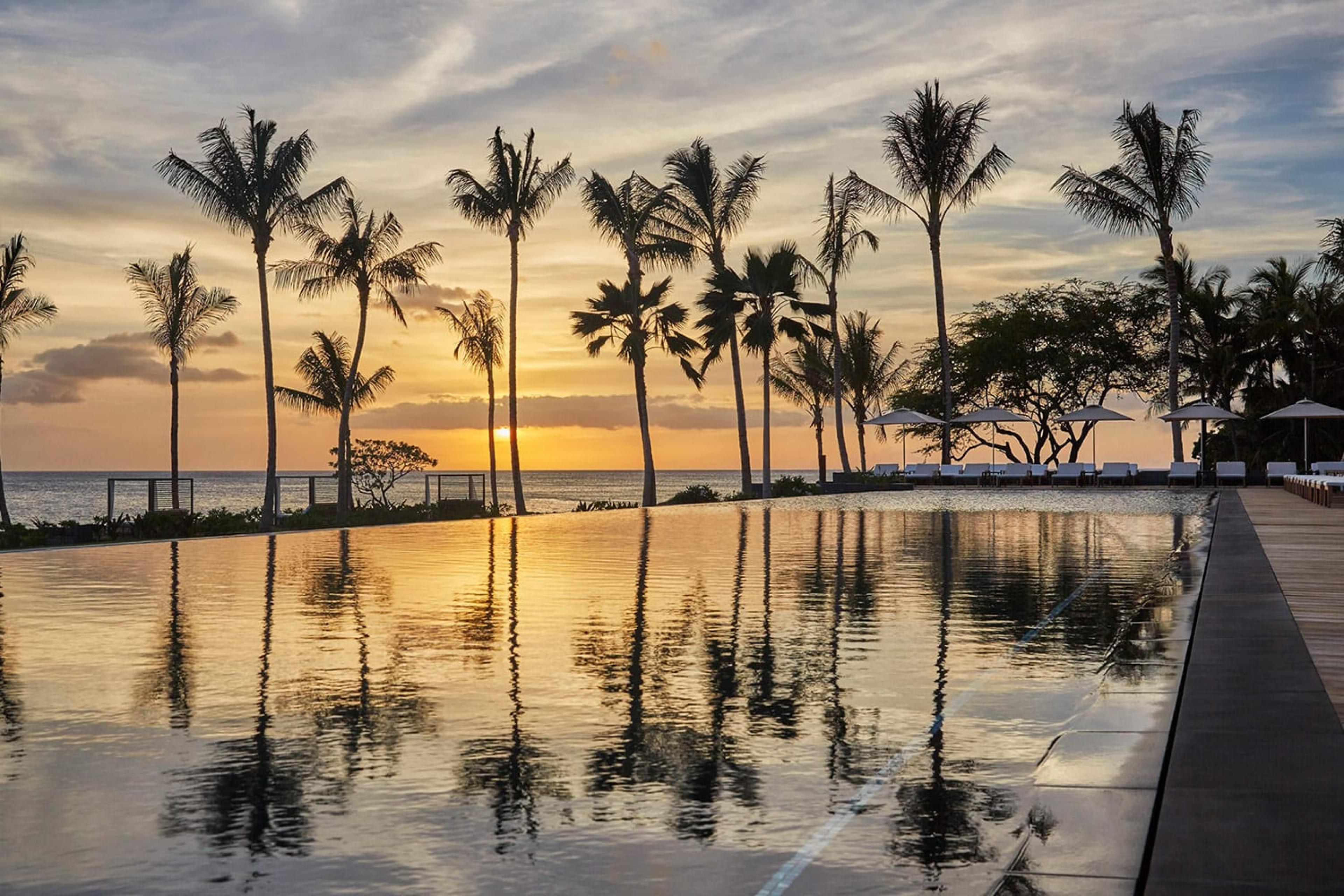 sunset over a pool with palm trees reflecting