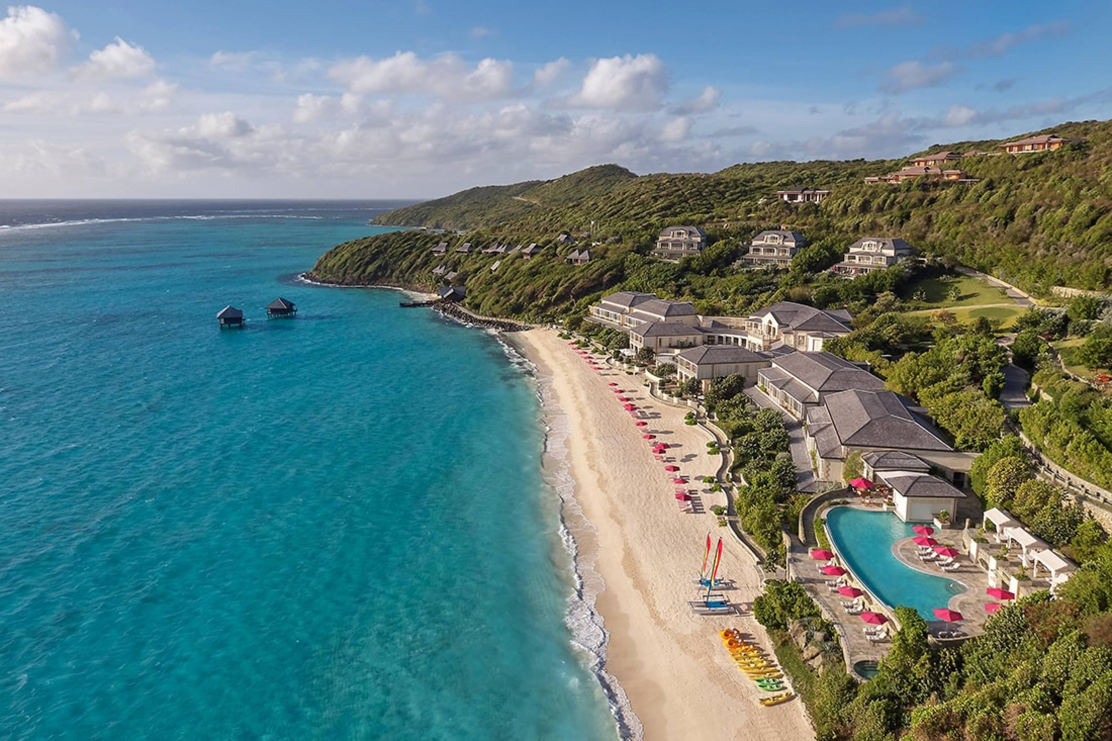 aerial view of caribbean resort complex built into slope of hill with pool and beach