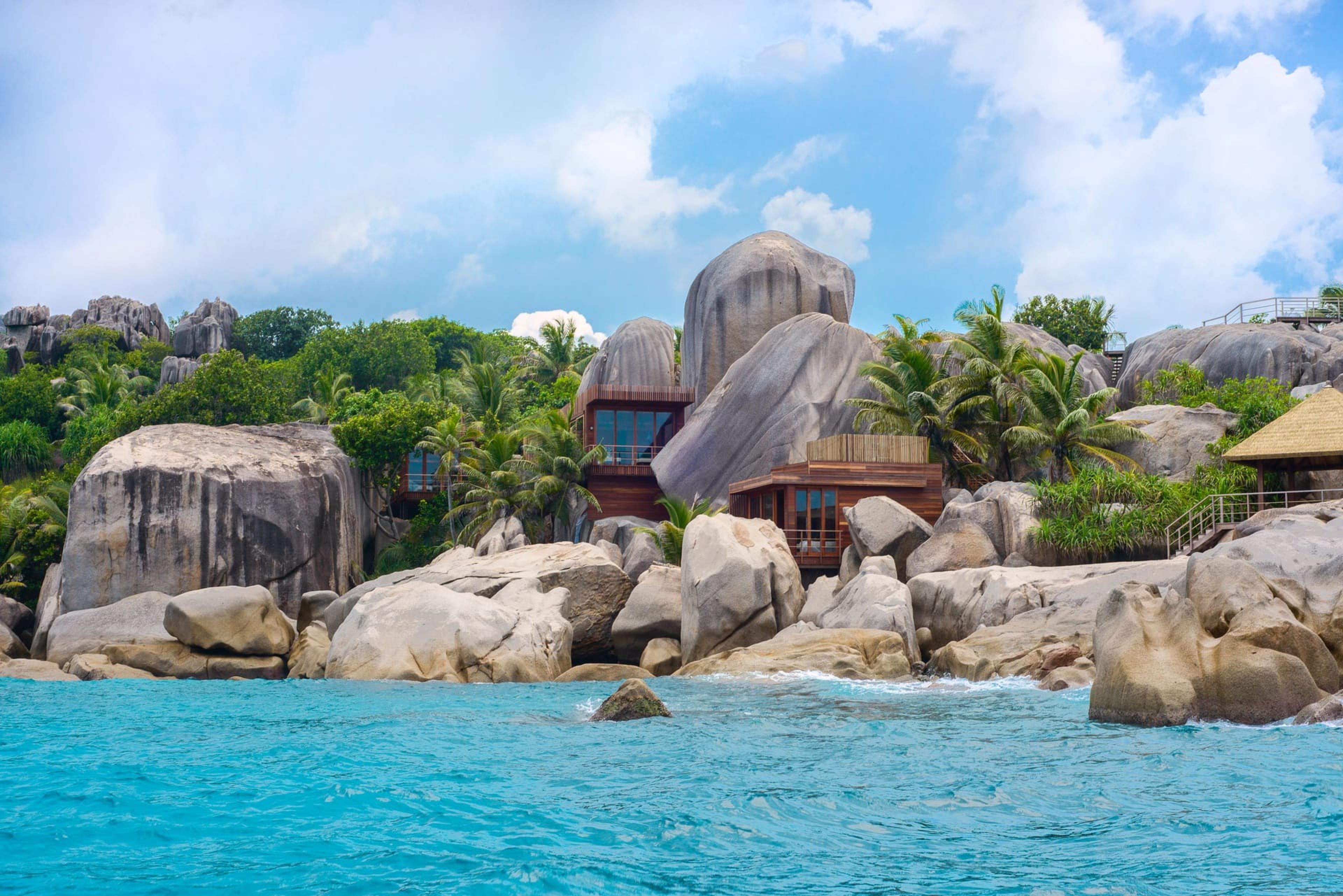 view from water looking towards big boulders on tropical island