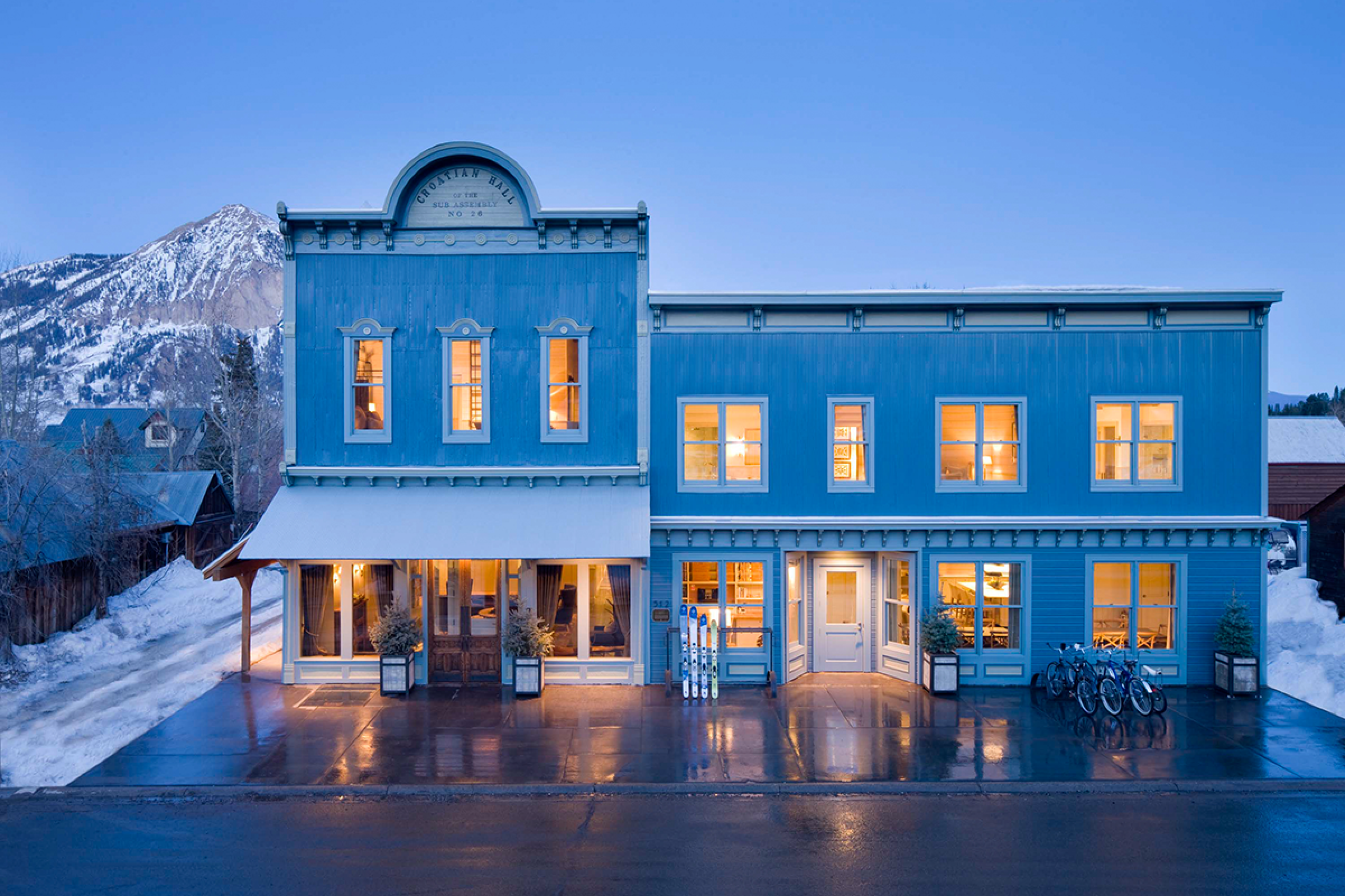 Blue hotel (looks like a Wild West general store) with lights on. It's dusk outside so the lights are glowing