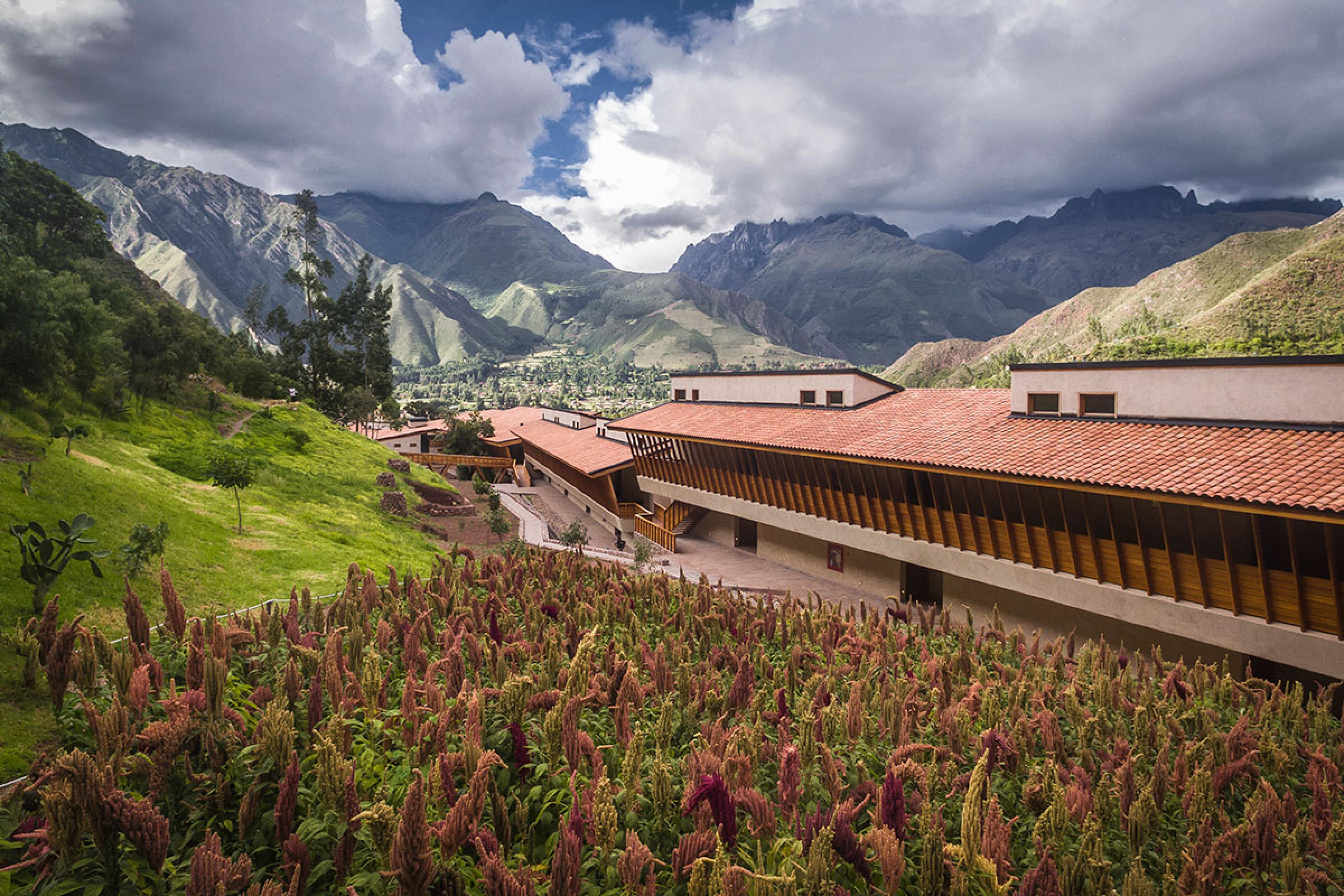 view of hotel exterior with red tile roof and long hotel building in a mountain valley