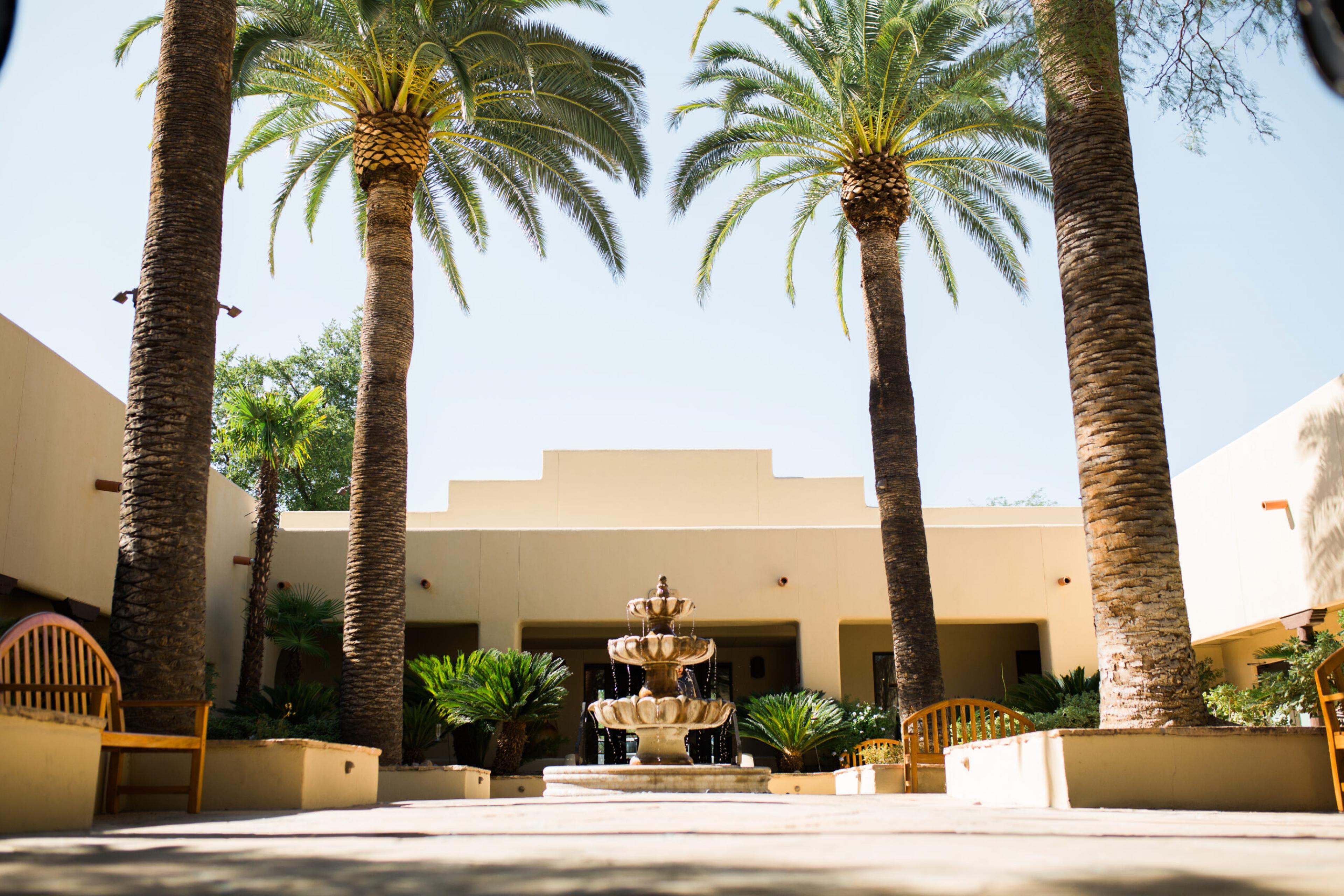 The entrance of Miraval is white adobe with two large palm frees framing the front door. There is a fountain in the middle of the courtyard.