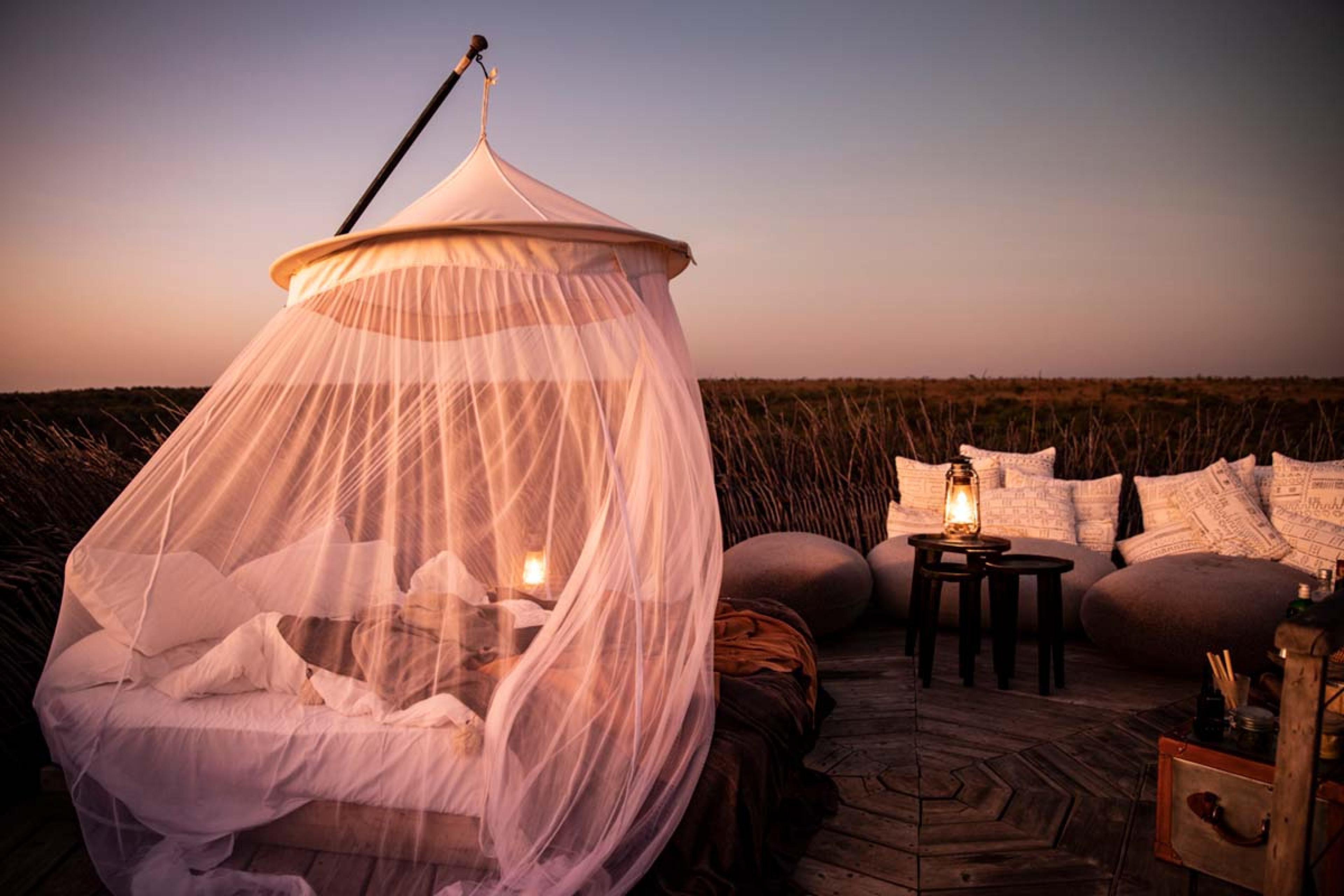 bed with mosquito netting on a patio in the middle of a the plains