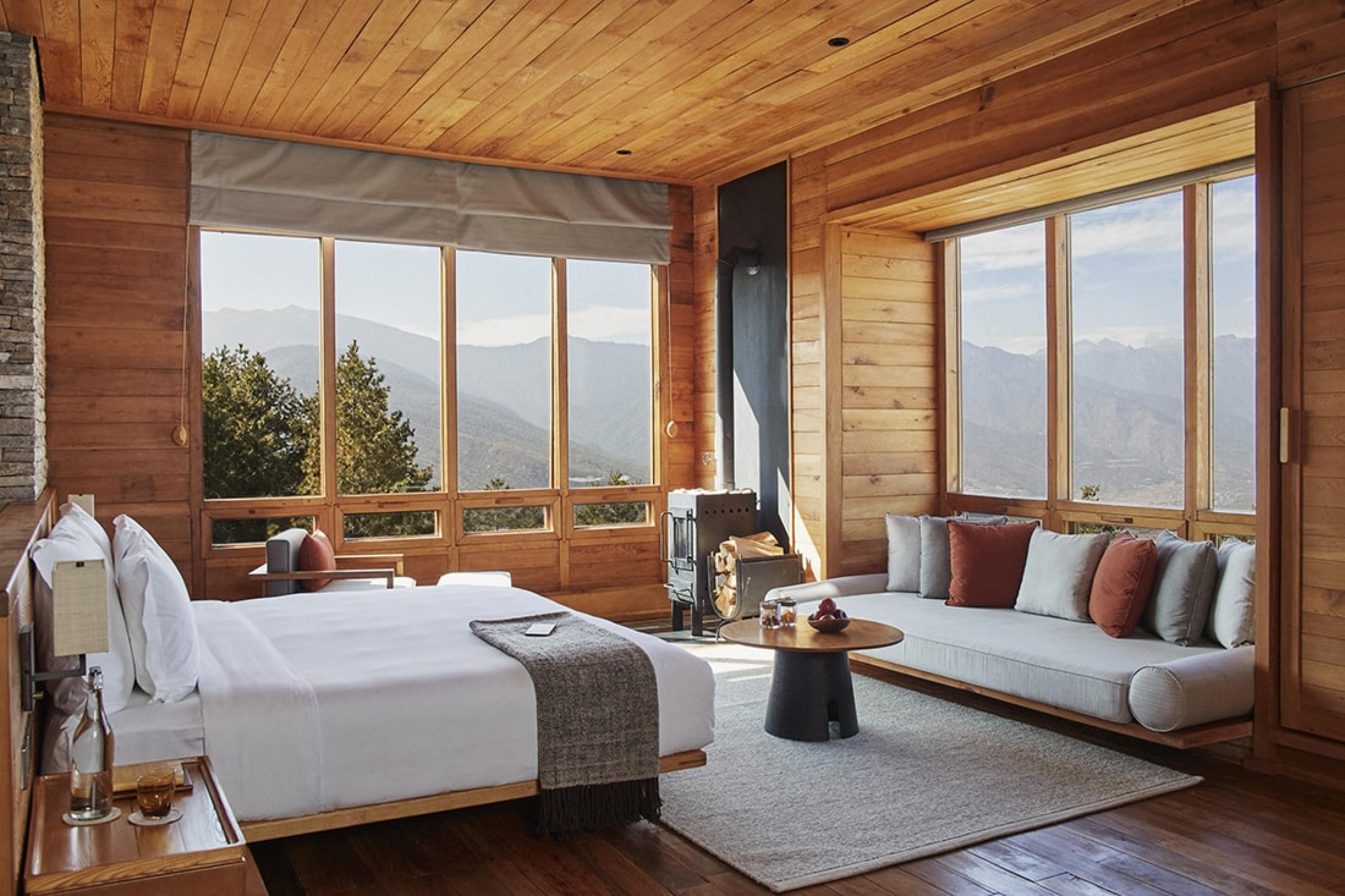 a bed and couch in a hotel suite with views over bhutan valley landscape