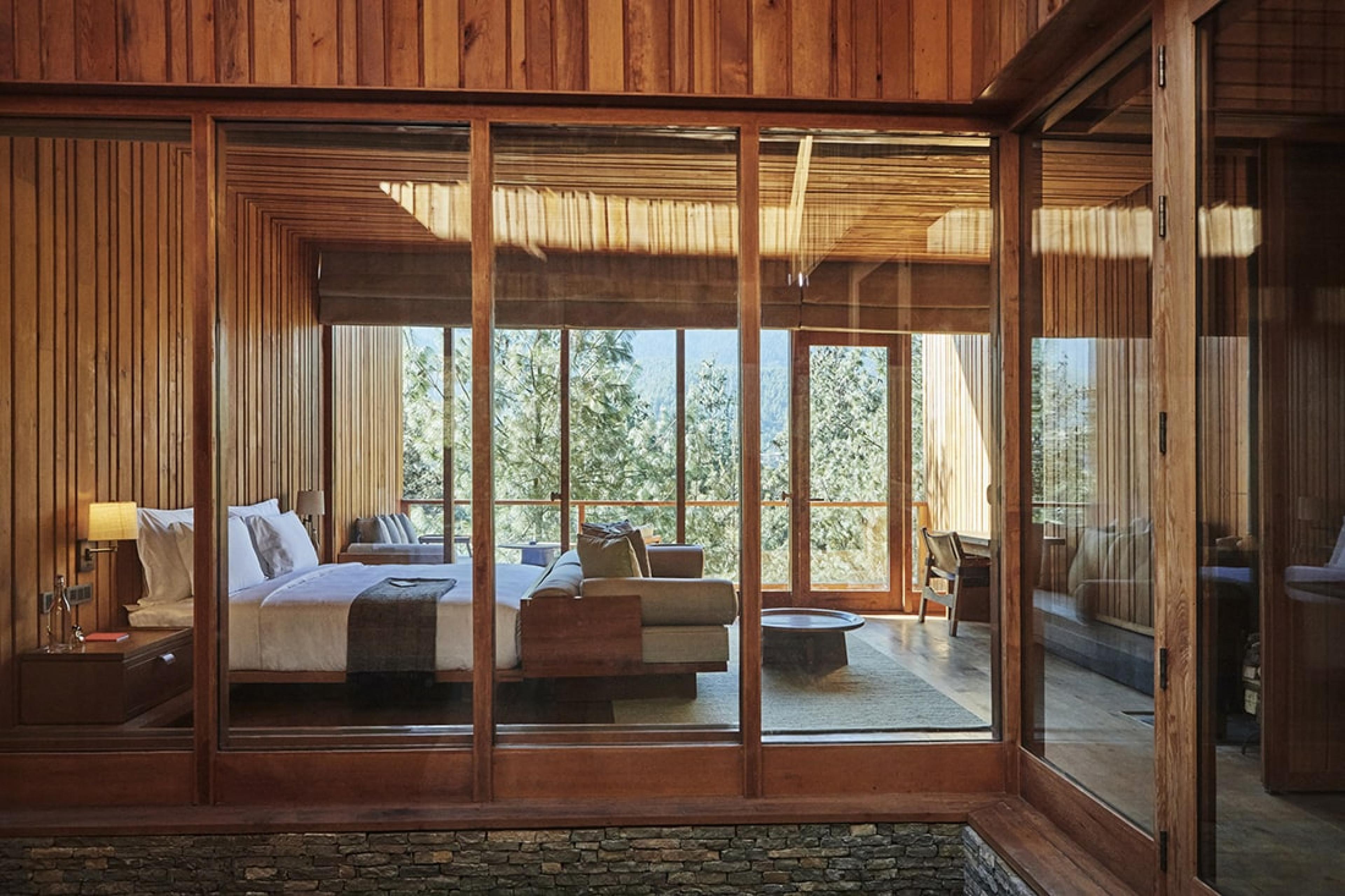 suite with wood paneling on wlls and bed on raised platform with view of trees in background