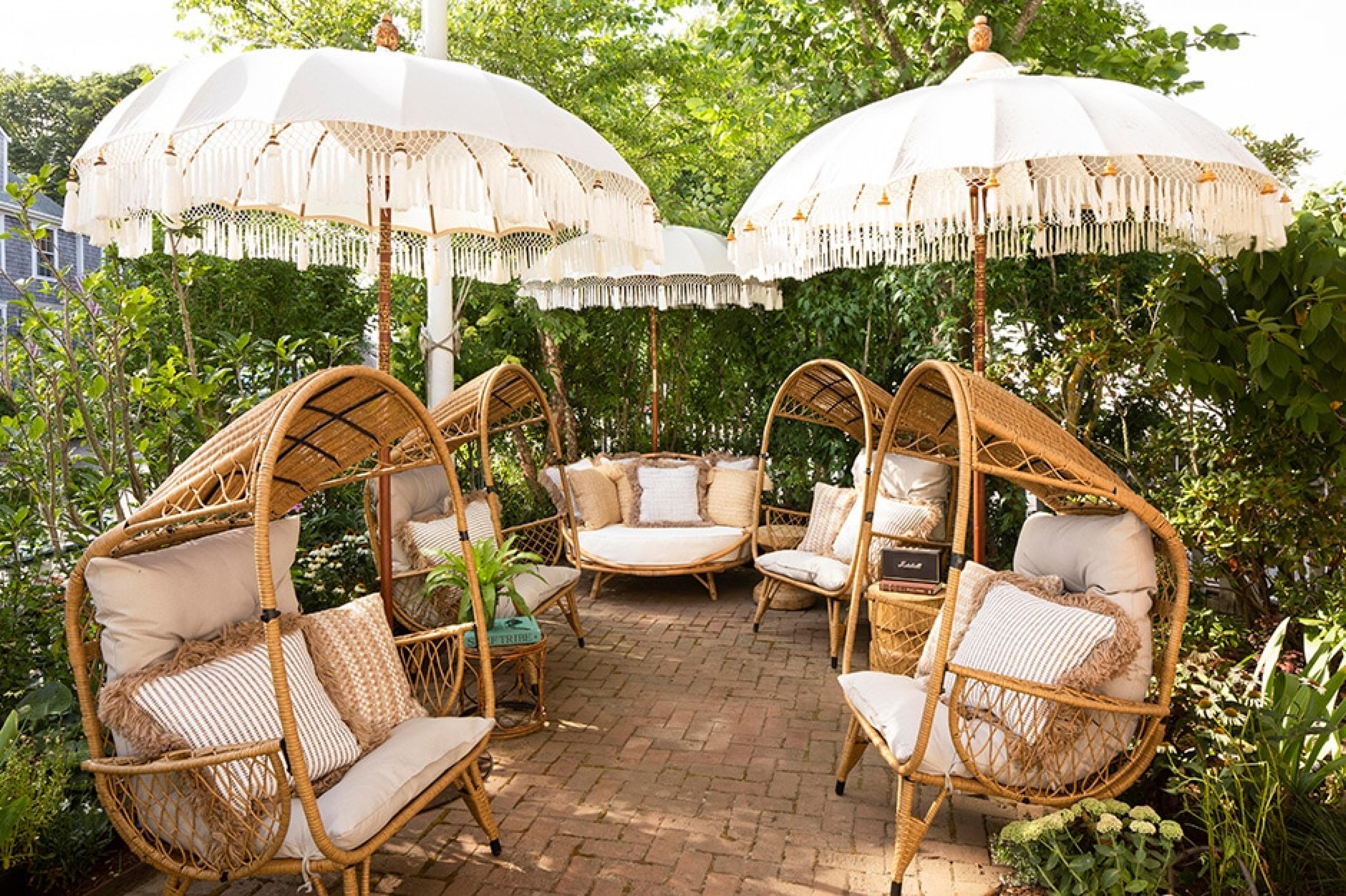 sets of rattan chairs and tassled sun umbrellas outside in a garden