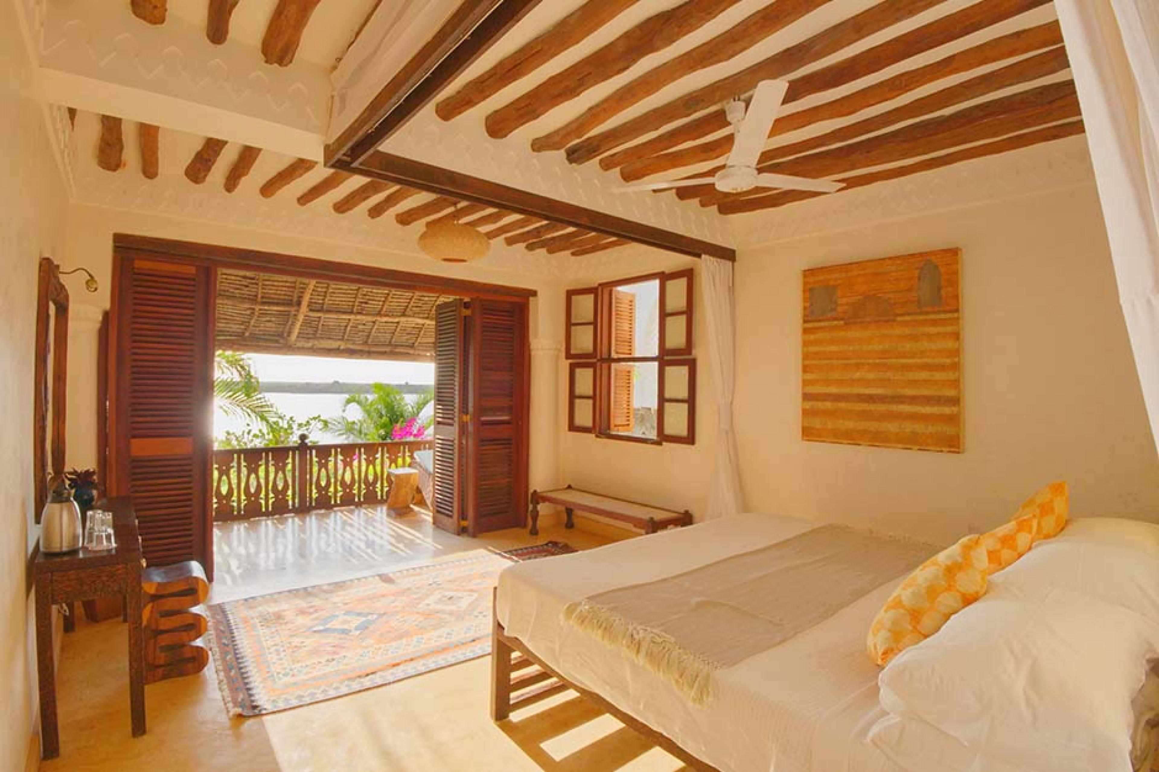 bedroom with african decor and double doors open on the ocean