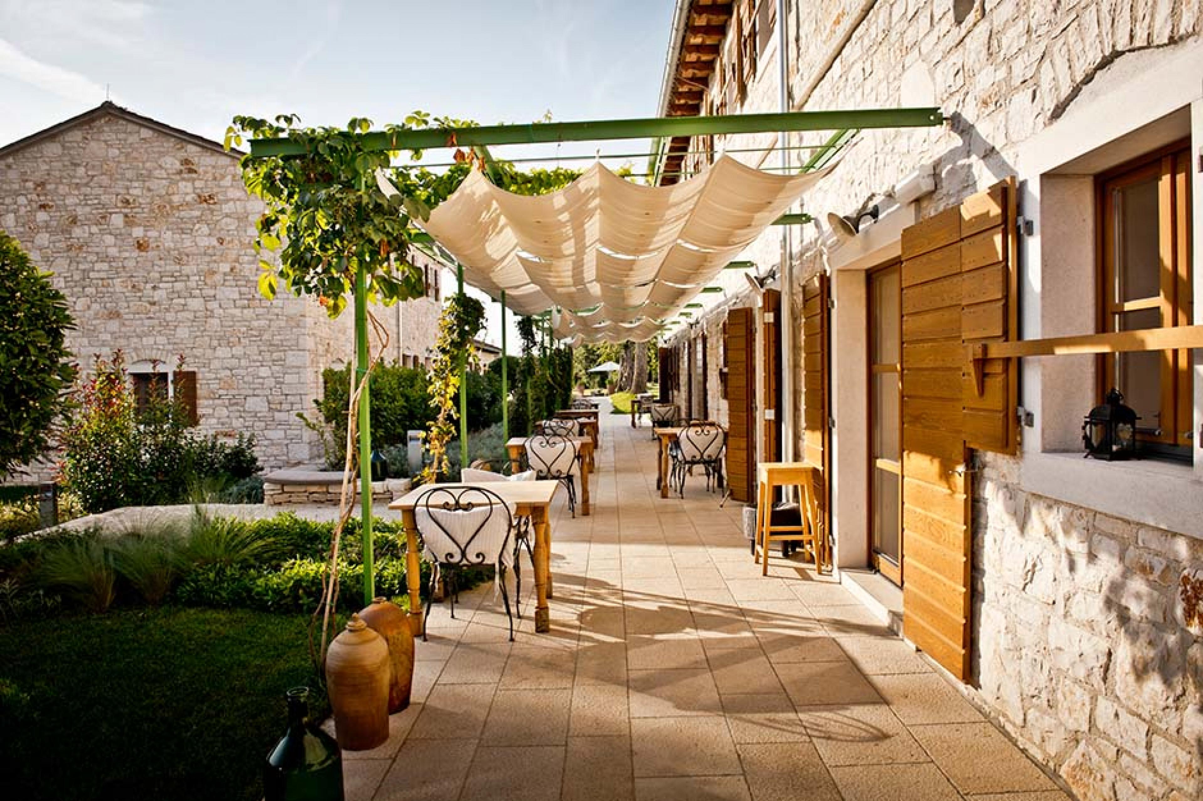 outdoor walkway surrounded by stone buildings with tables and chairs 