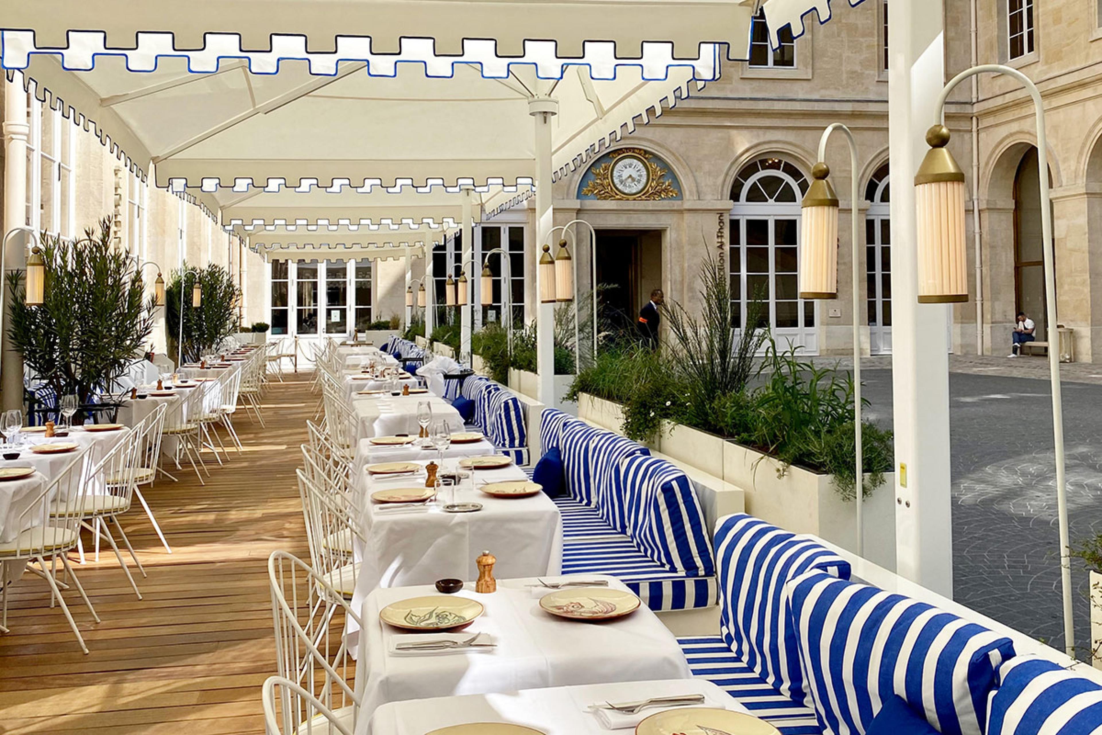 restaurant seating outside under white umbrellas in paris with blue seats
