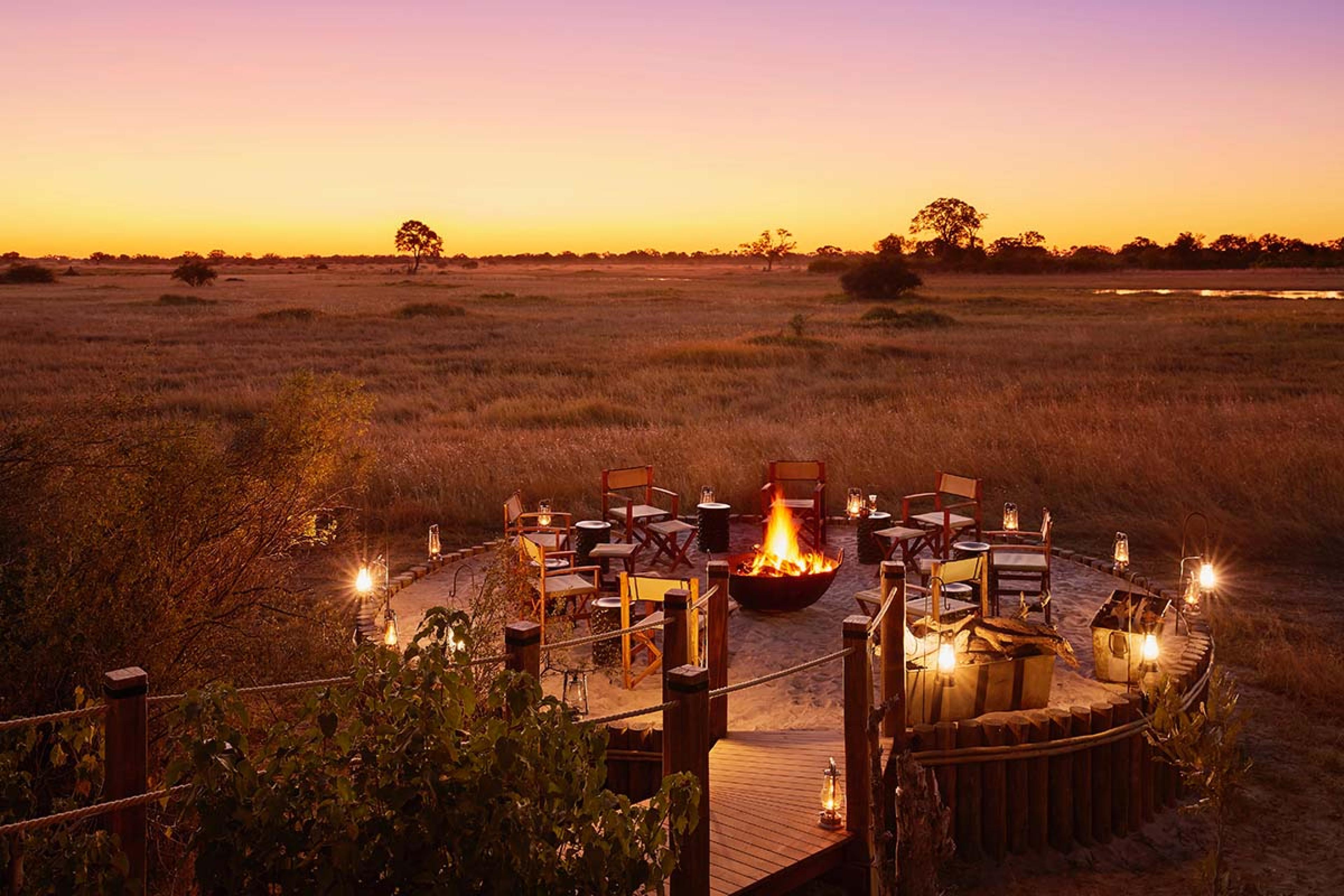 a fire pit surrounded by chairs in the middle of an African plain