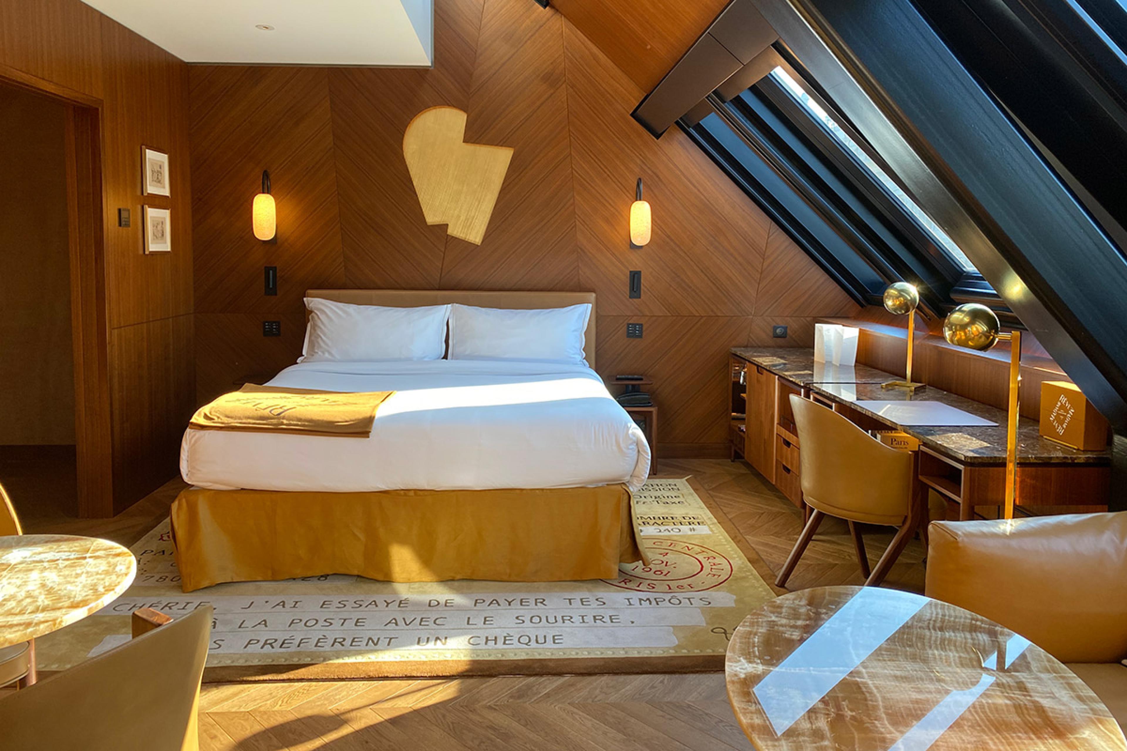 hotel suite with wooden walls and a white bed with slanted skylight windows