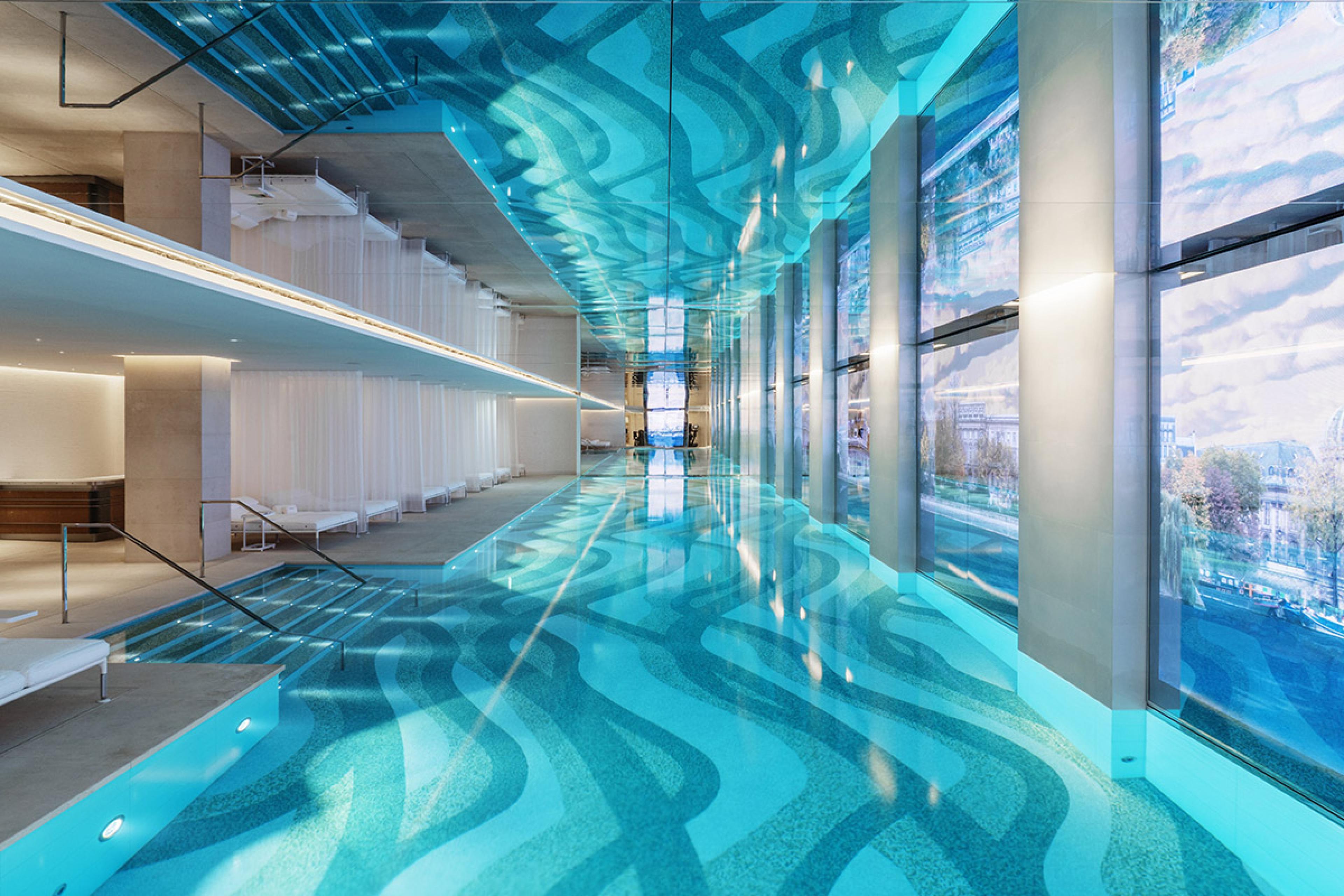 hotel pool inside with blue tiles and on the right a video wall showing the seine river 