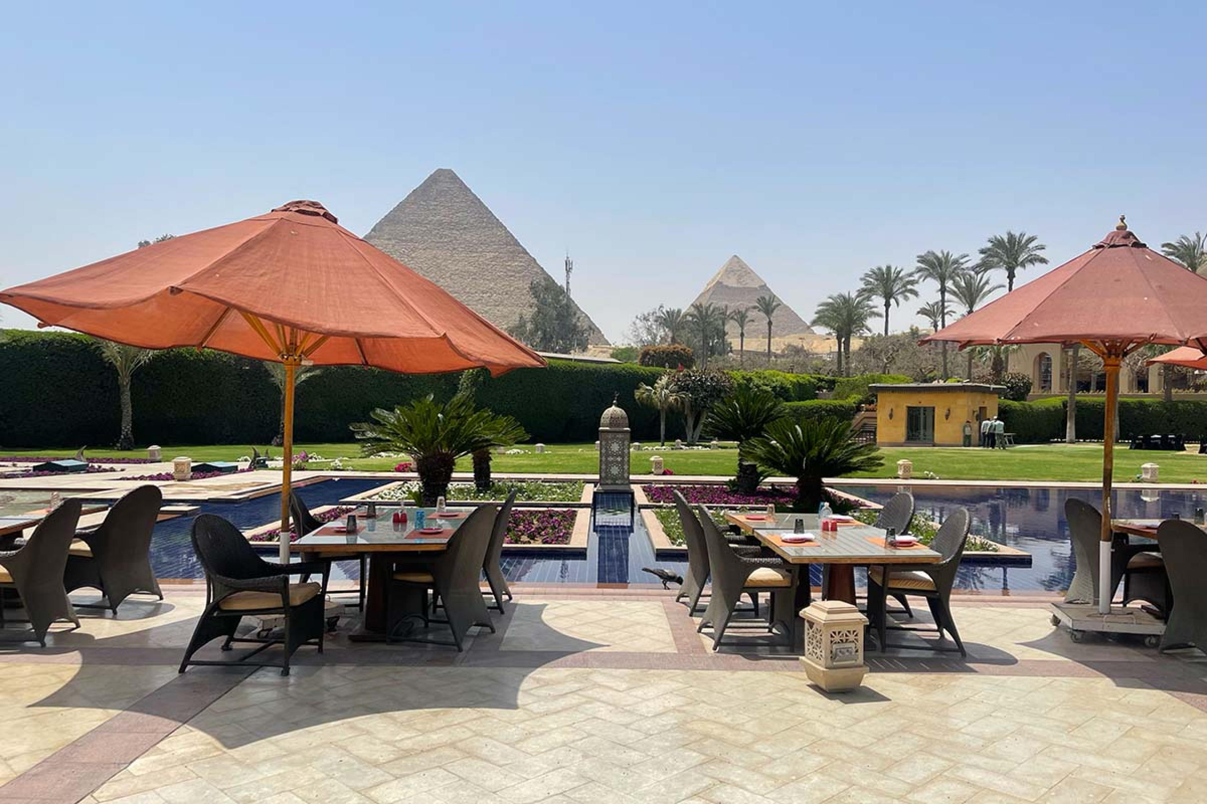 patio with dining tables around a pool with a pyramid in the background