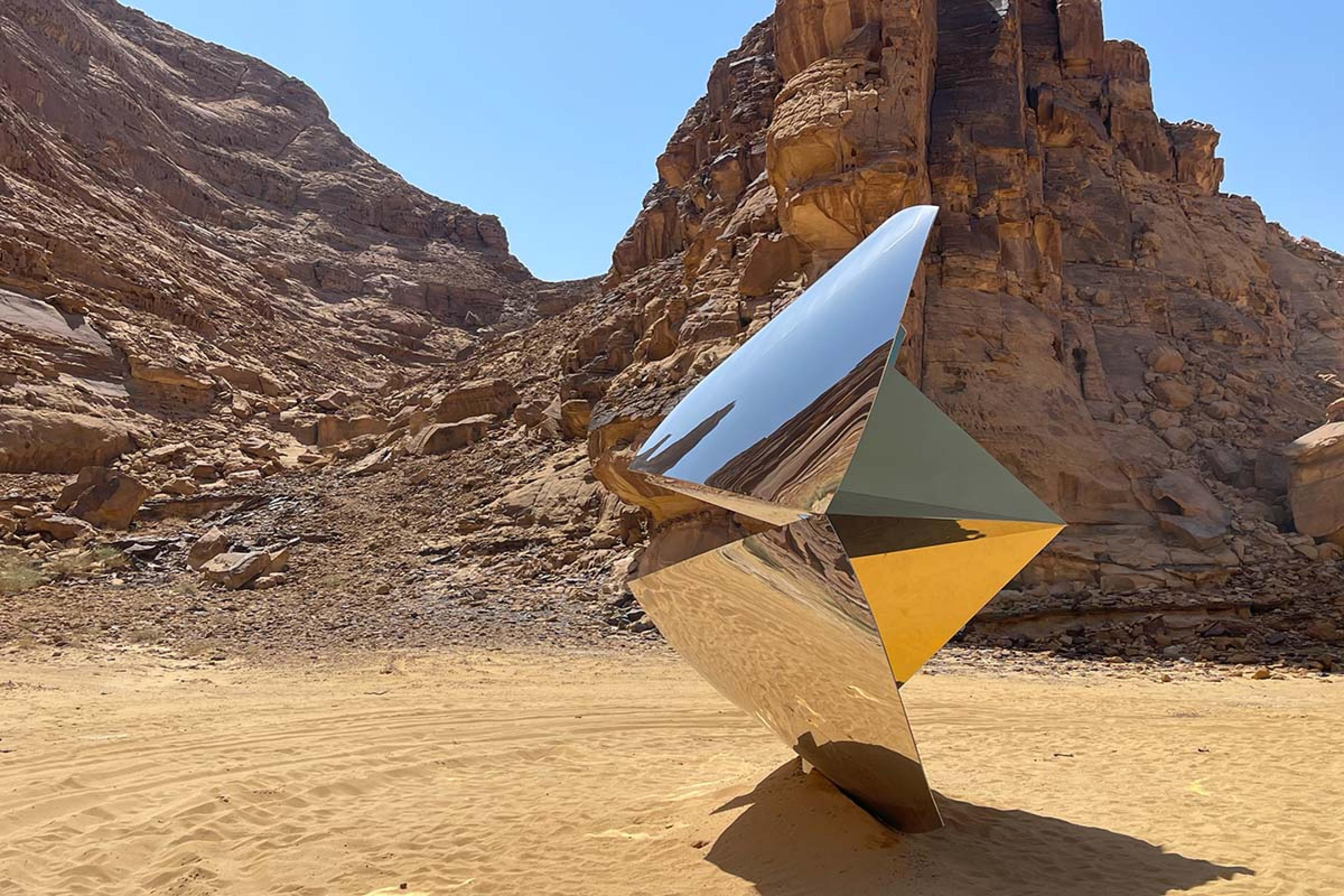 a metallic fortune cookie shaped sculpture in the desert