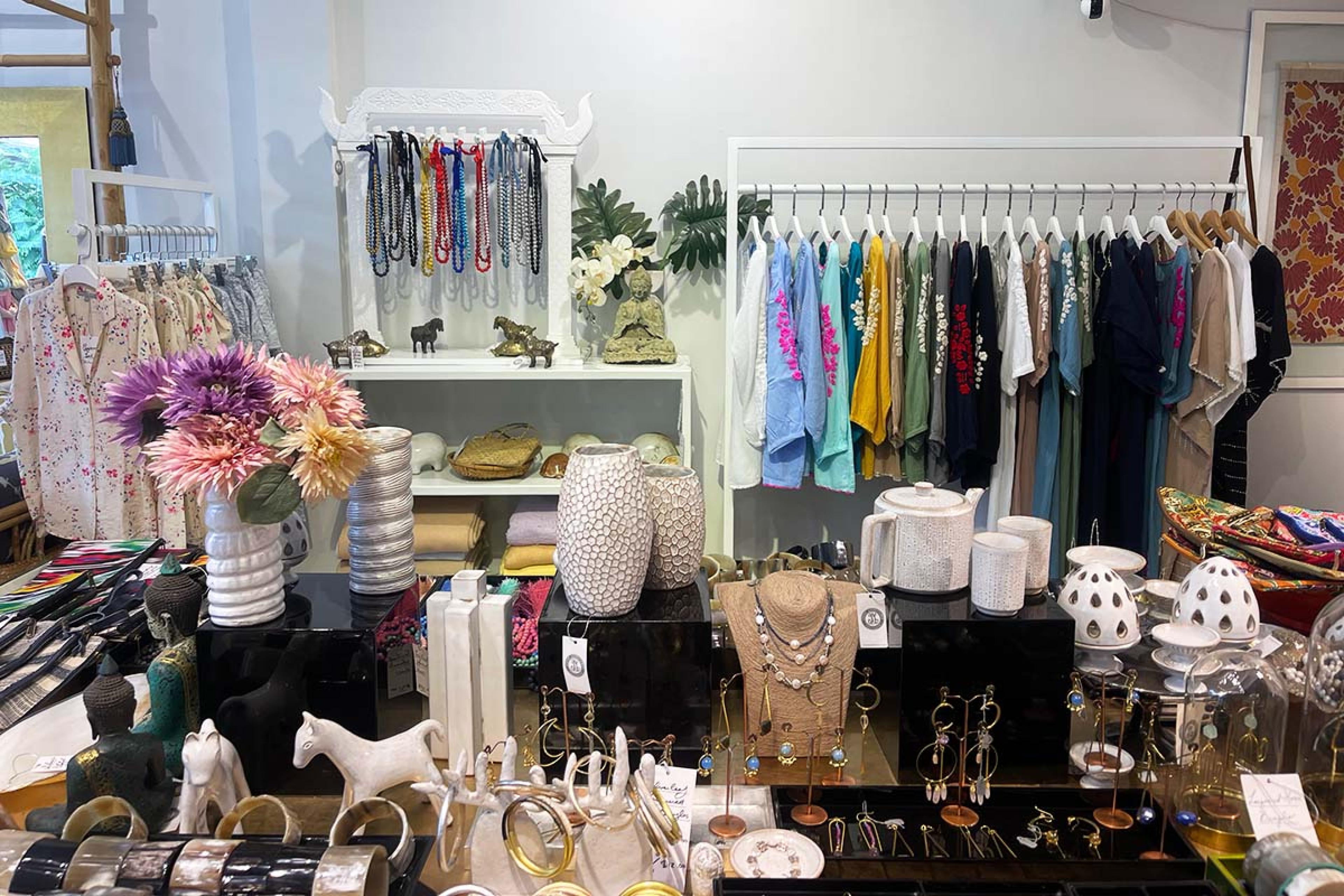 store interior with a rack of cloths and a table full of jewlery