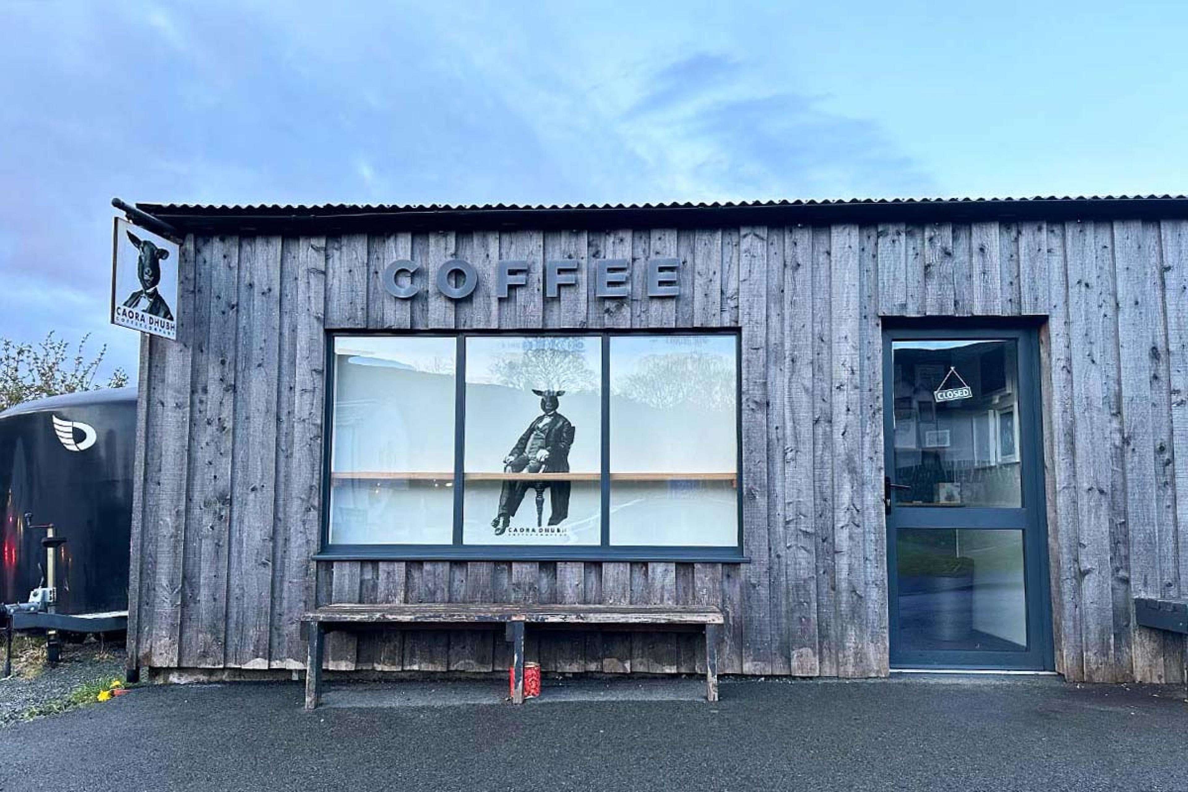 wooden building with a sketch in the window and coffee on a sign above it