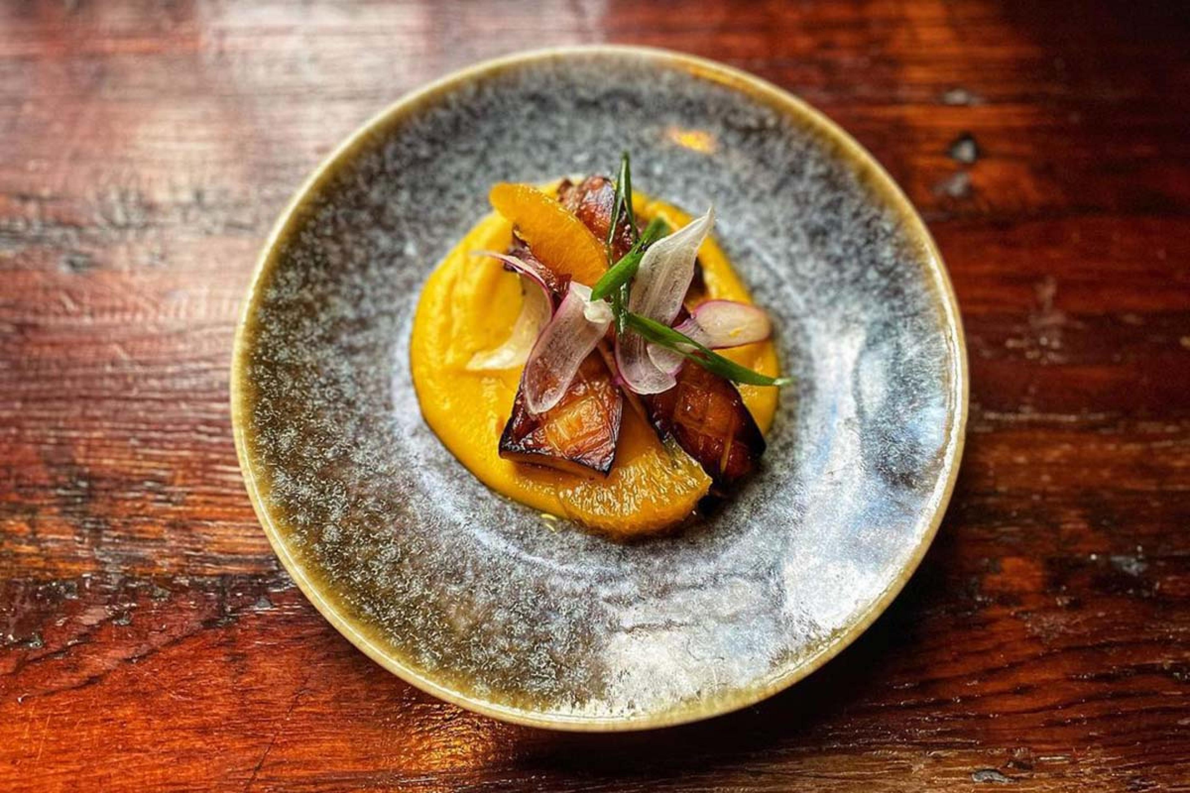 Pan-Roasted King Trumpet Mushroom with Satsuma and Butternut Squash Purée on a stone plate