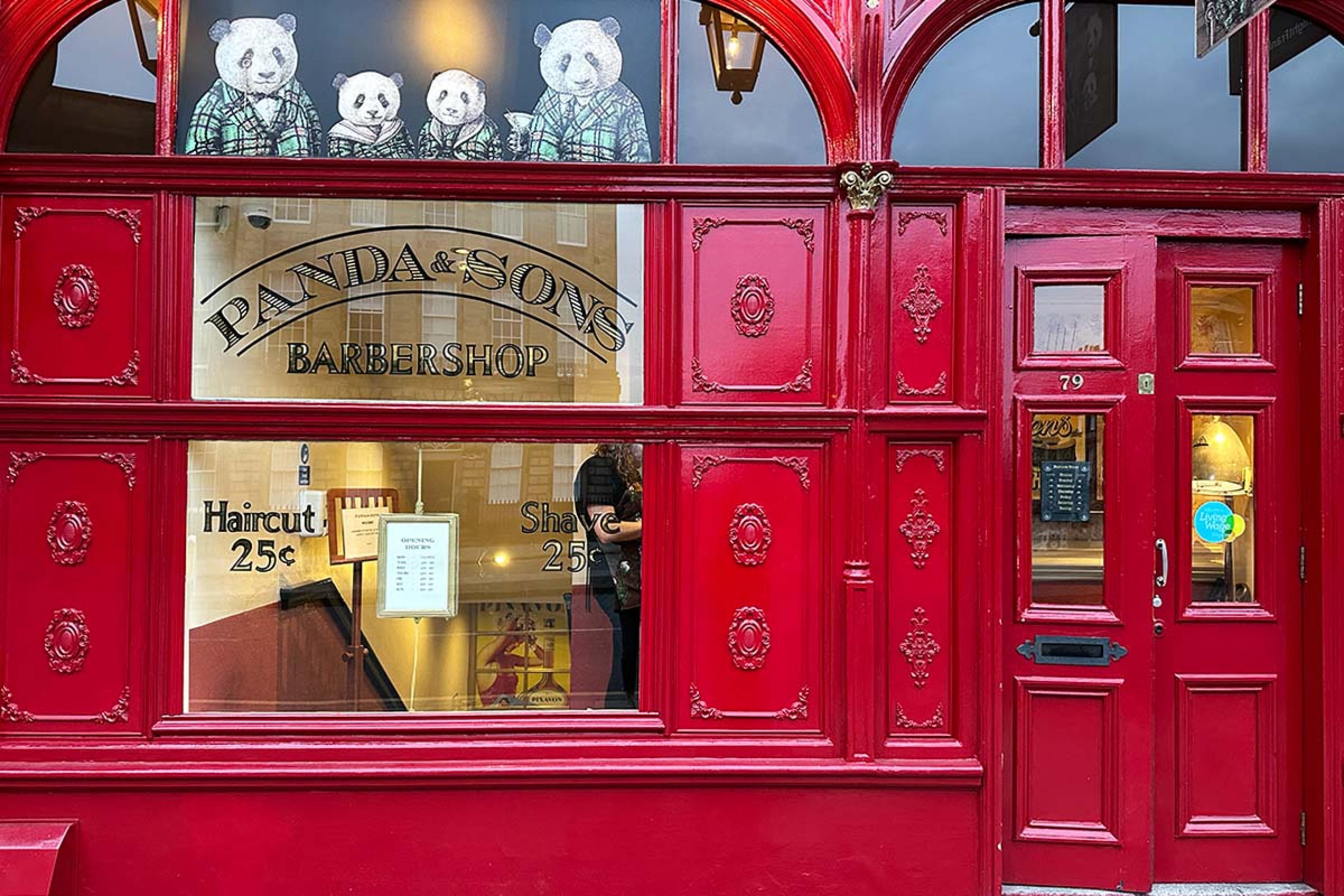 shiny red store front with a photo of pandas in suits over the window
