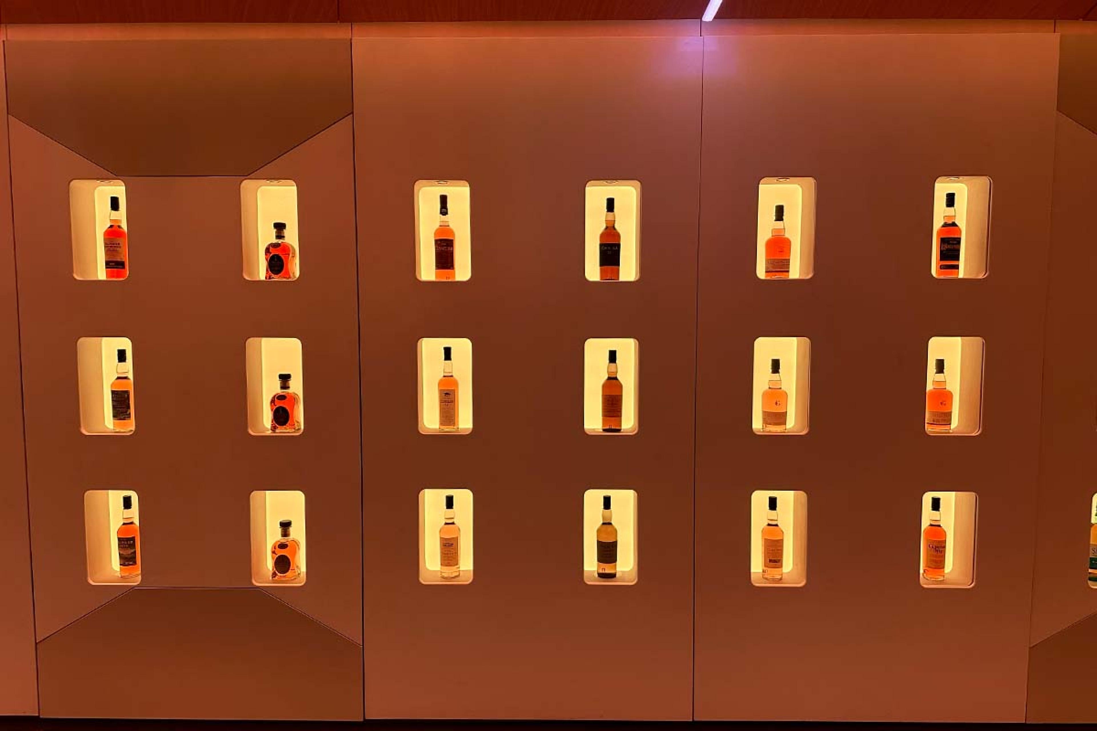 warm brown wall with individual inset lit shelves displaying whisky bottles