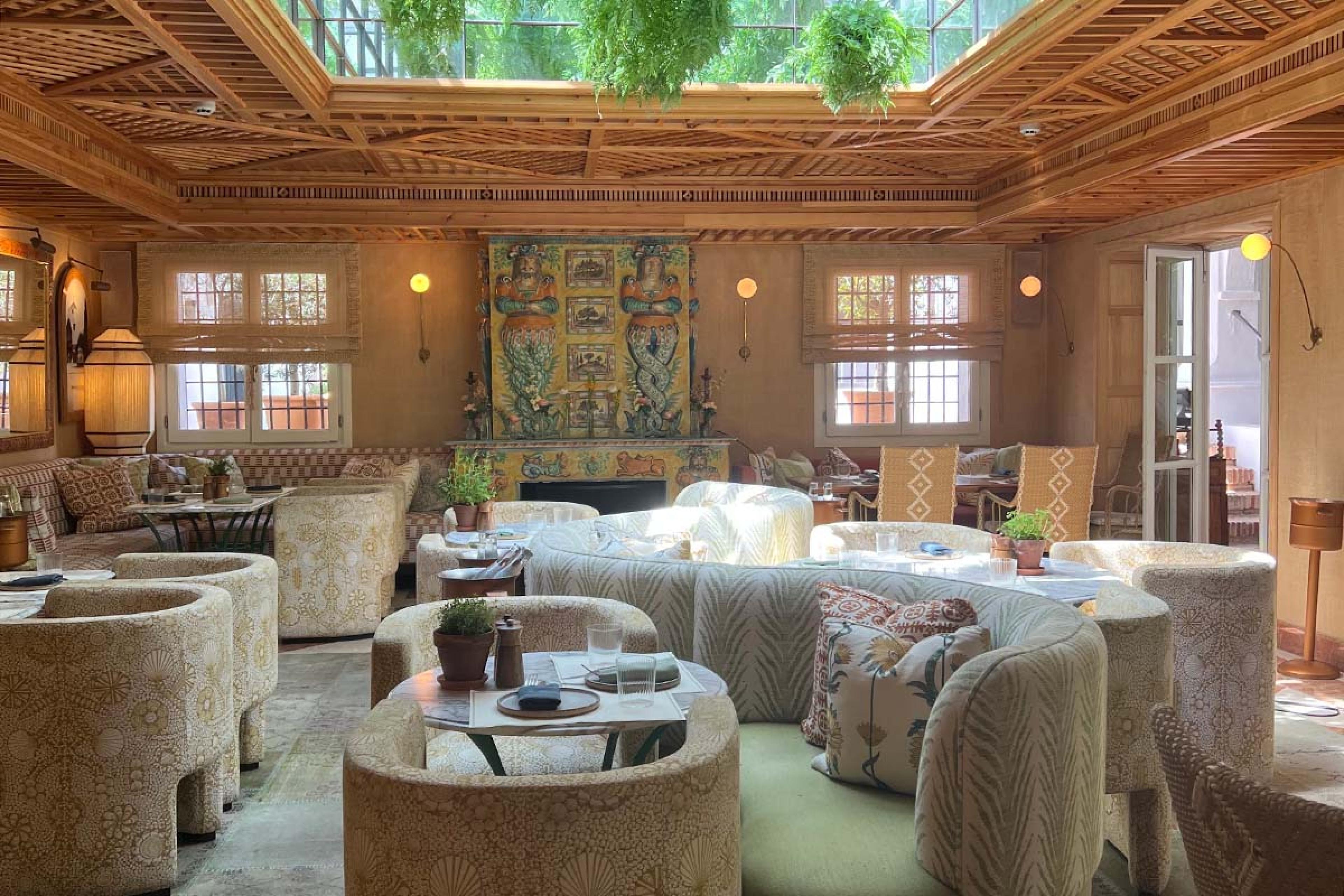 lounge with with patterned cushioned chairs, a woven wooden ceiling and sea creature paintings on the wall