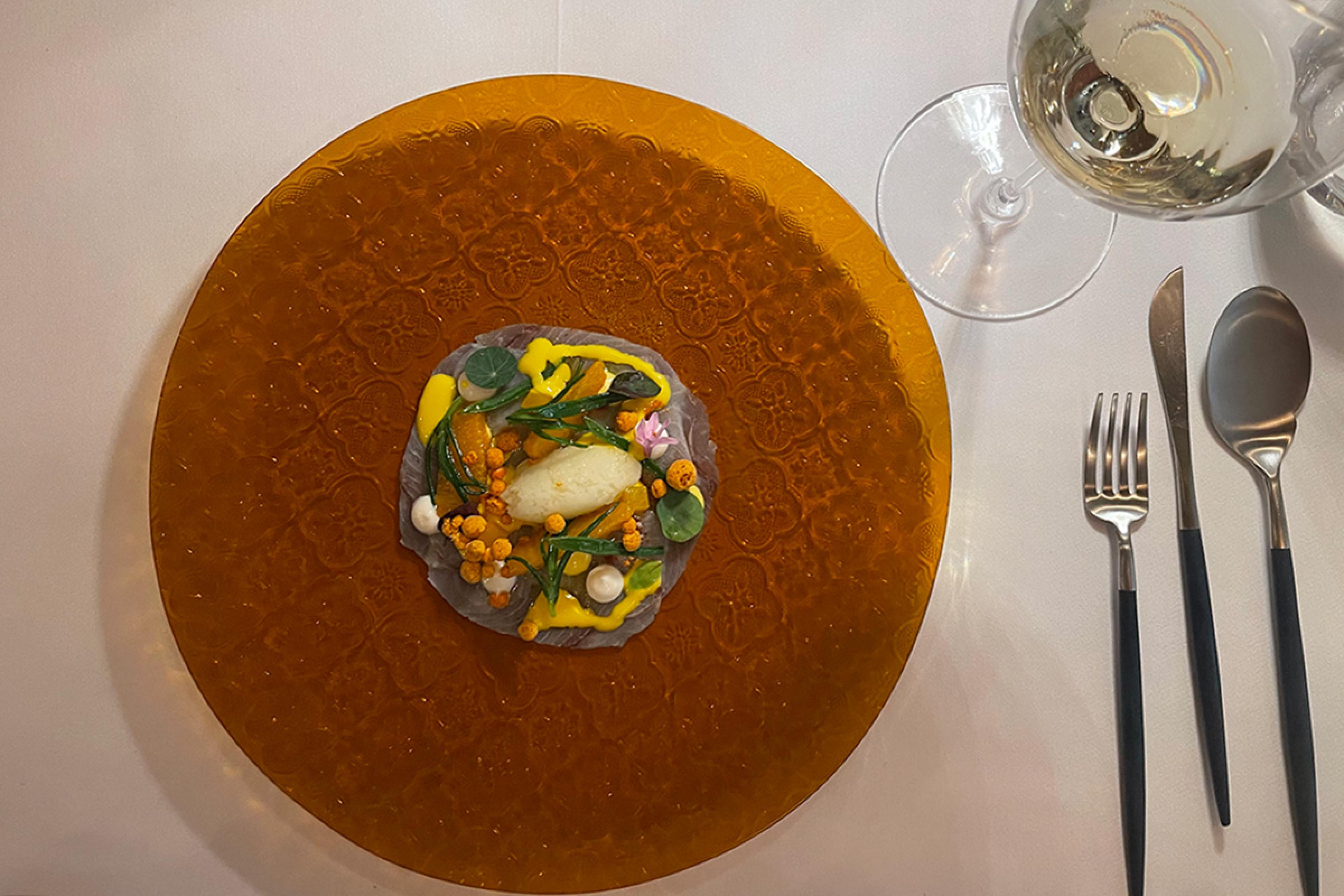 view of orange glass plate with fine dining food on it