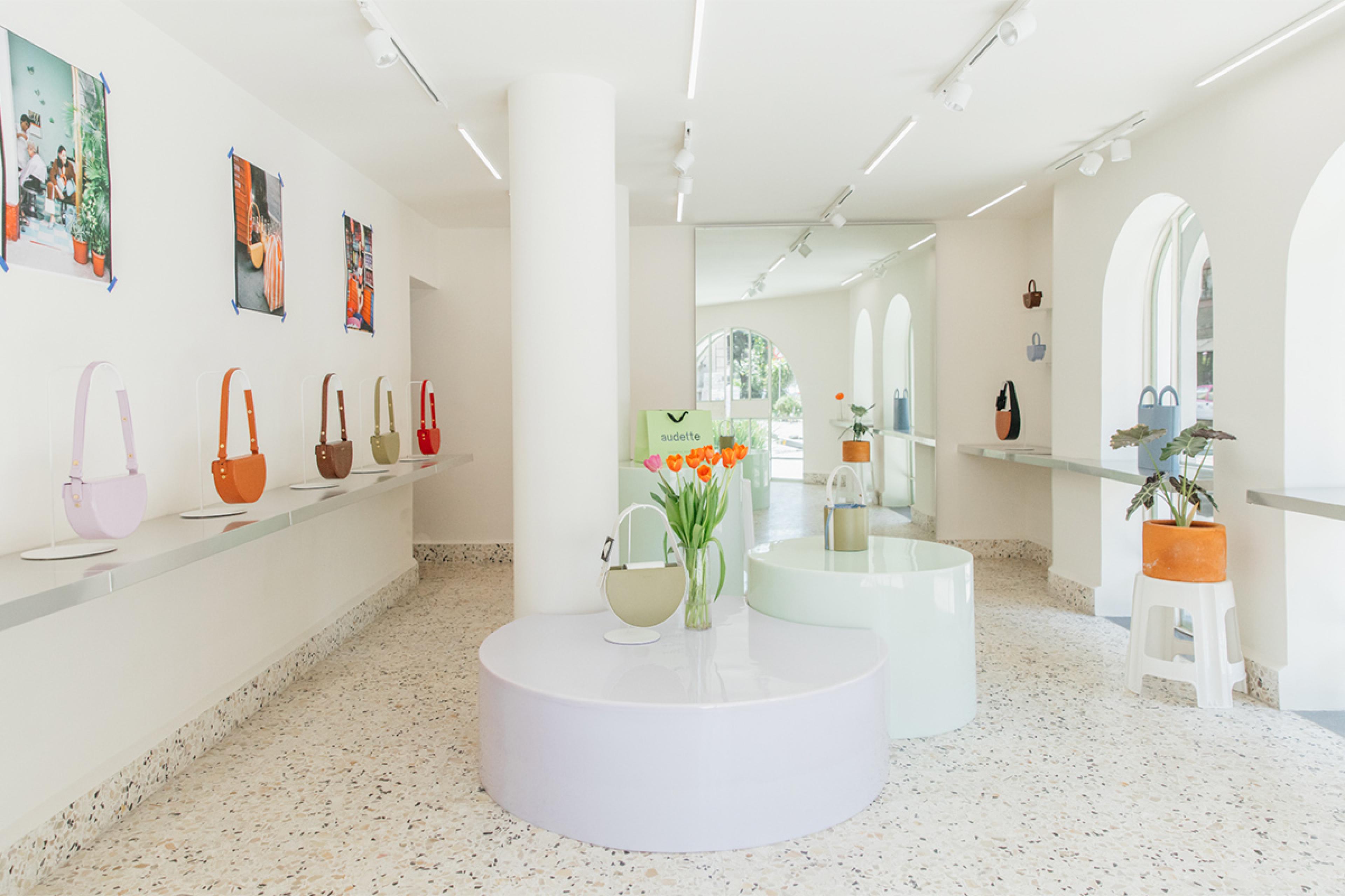 store in mexico city with white walls and terrazzo floors that has colorful purses for sale on the wall
